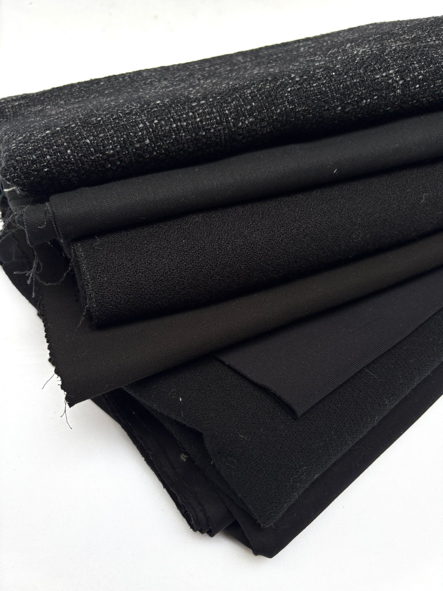 Stack of black fabrics in various textures 