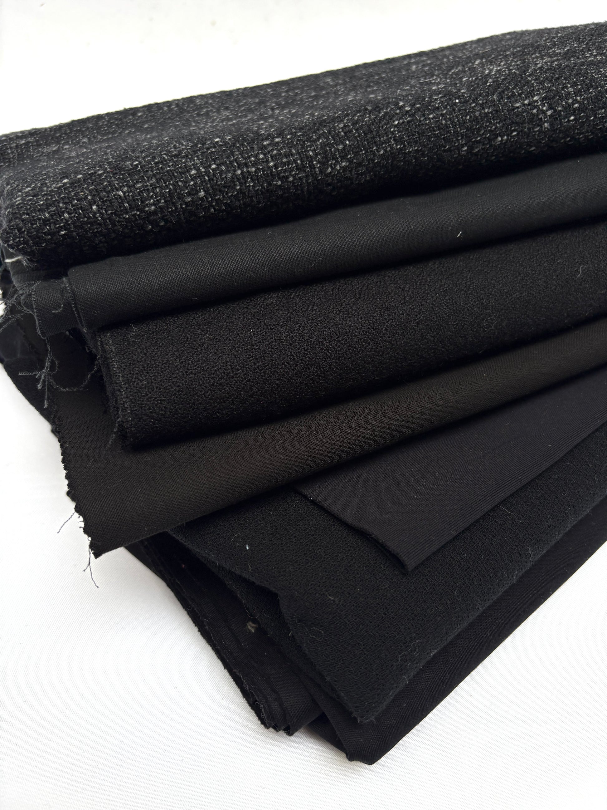 Stack of black fabrics in various textures 