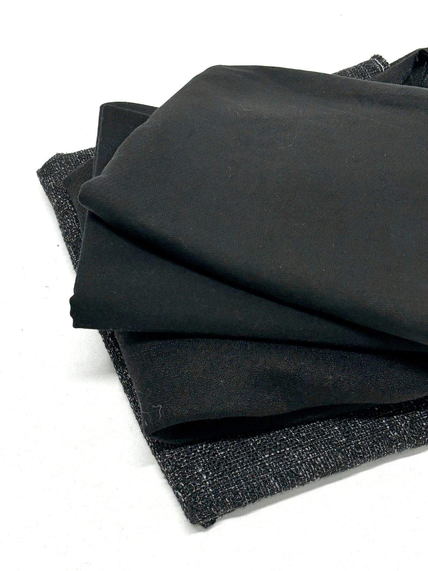 Stack of black fabrics in various textures 
