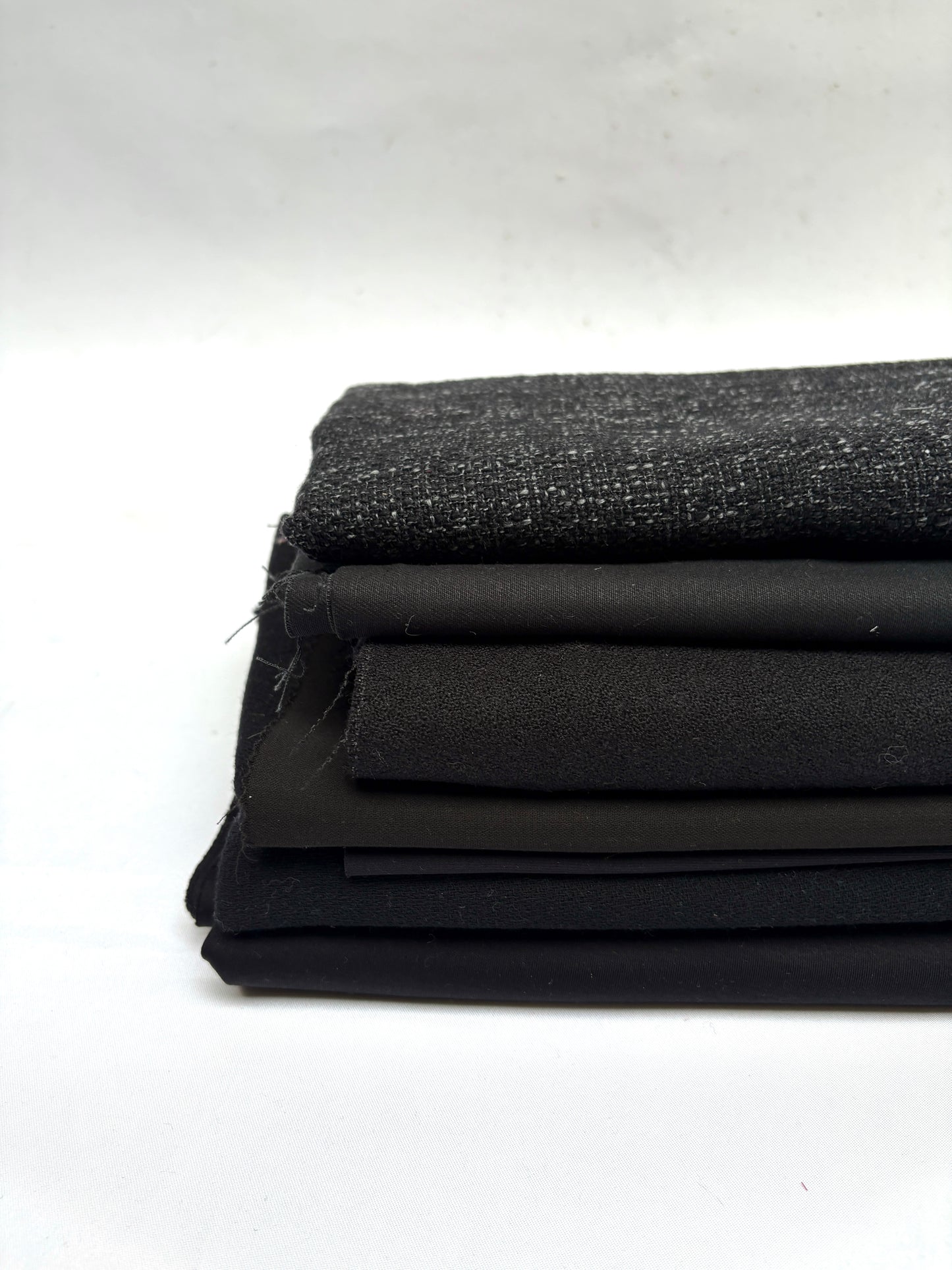Stack of black fabrics in various textures 