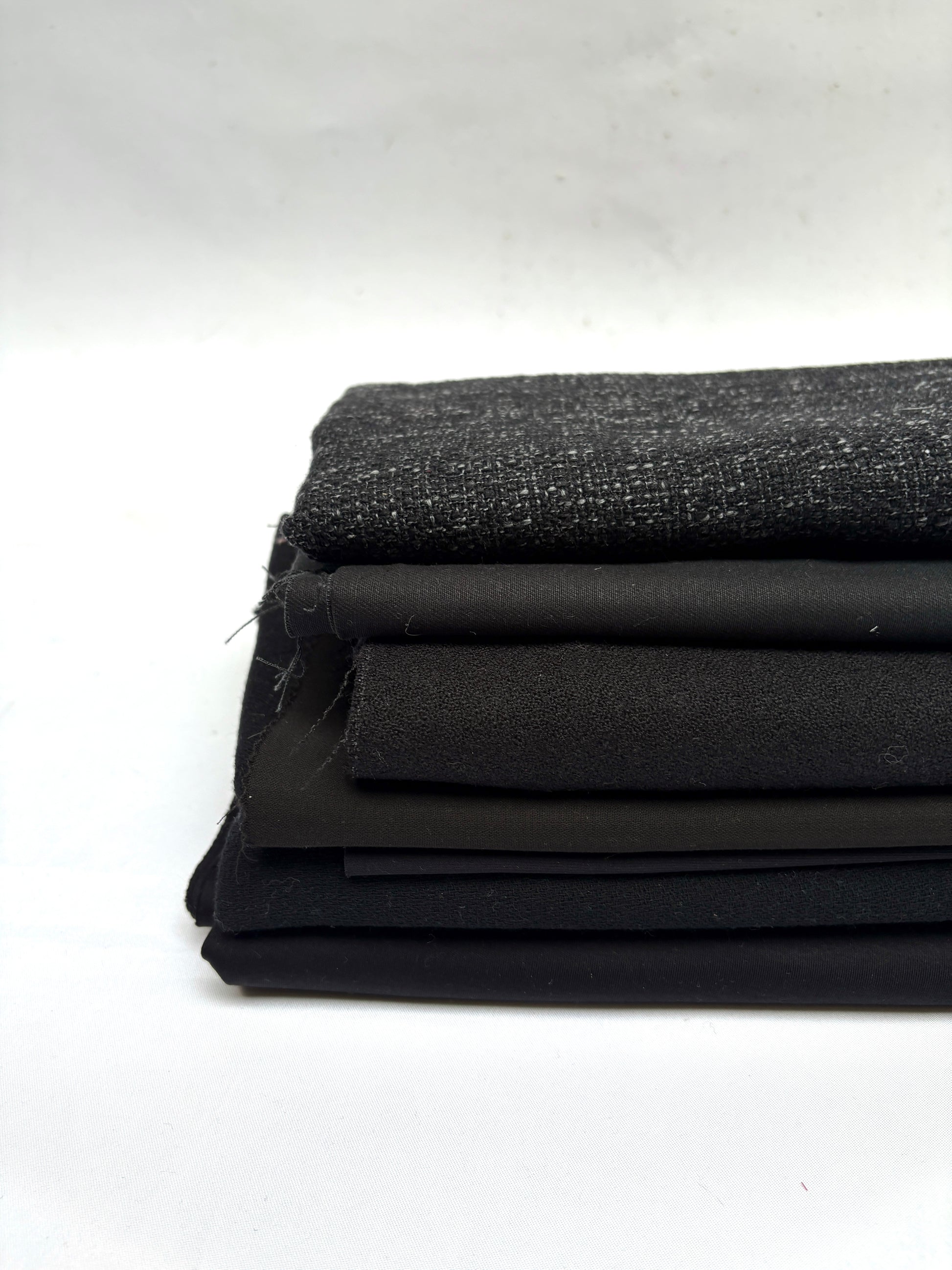 Stack of black fabrics in various textures 