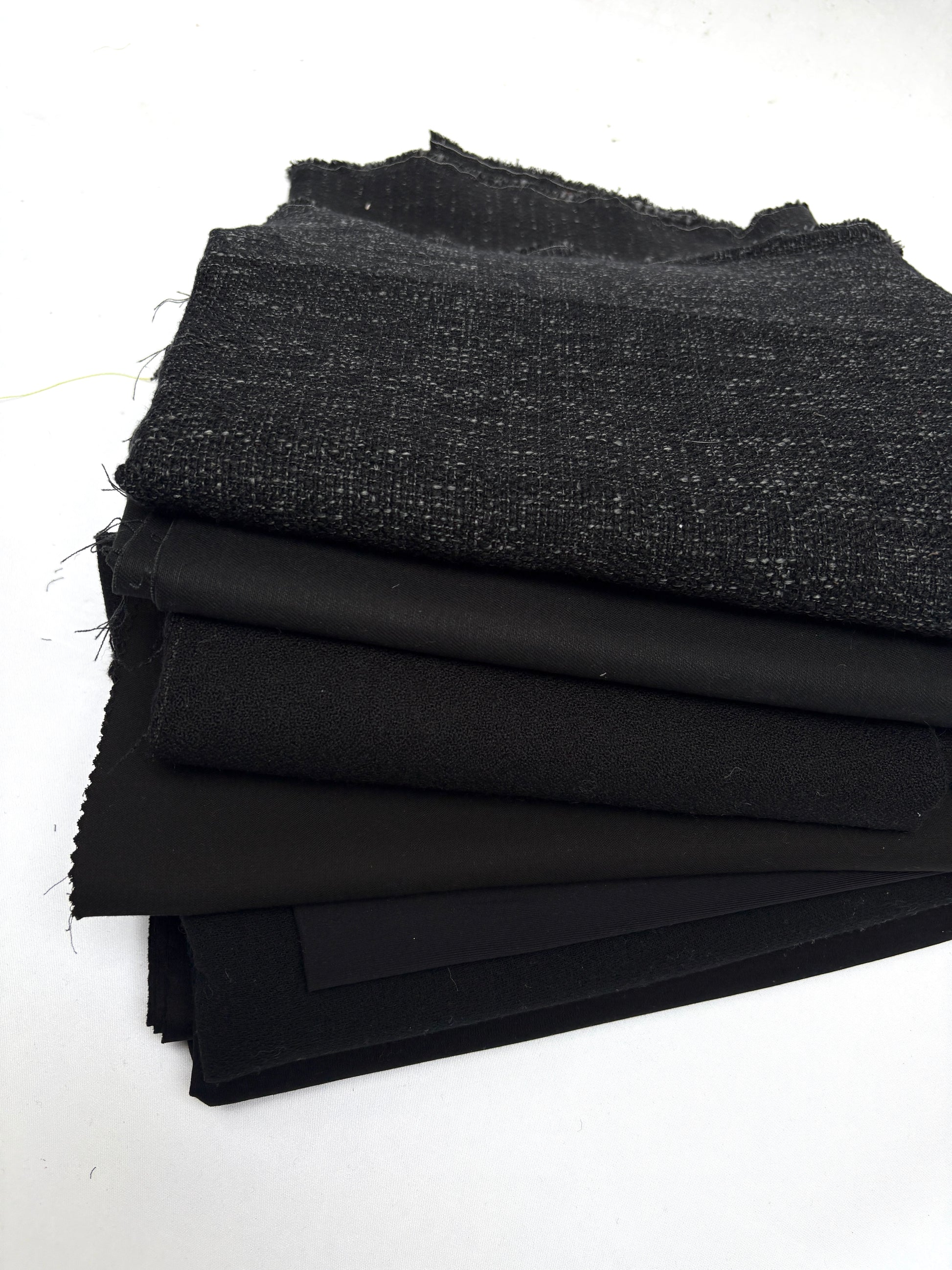 Stack of black fabrics in various textures 