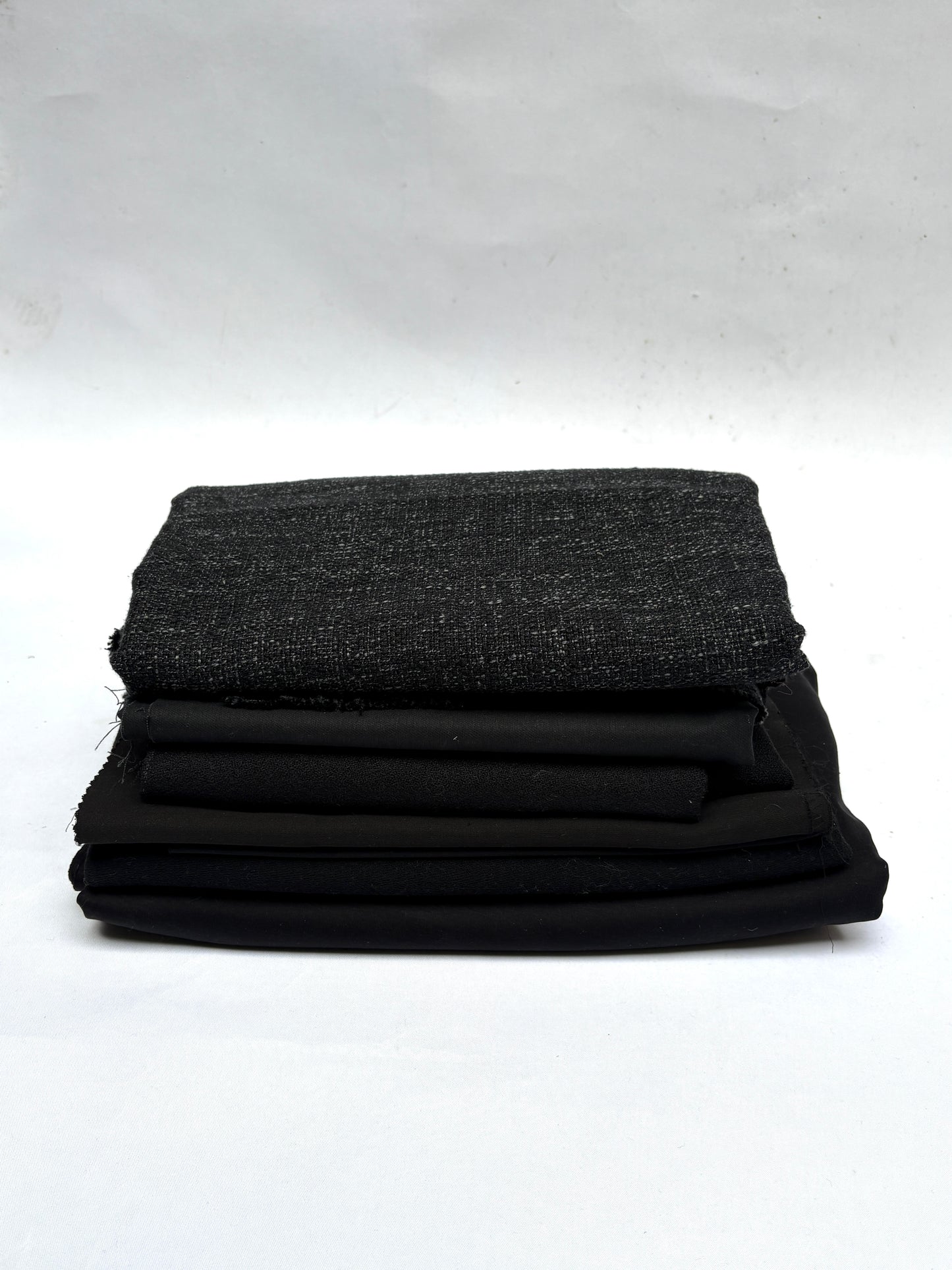 Stack of black fabrics in various textures 
