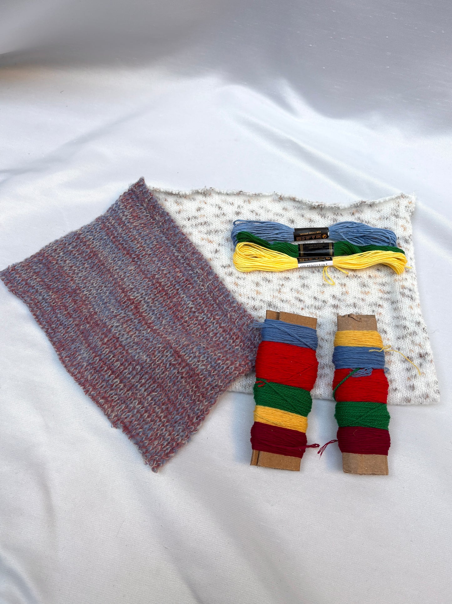 Textured fabric swatches with bright thread spools and embroidery floss.