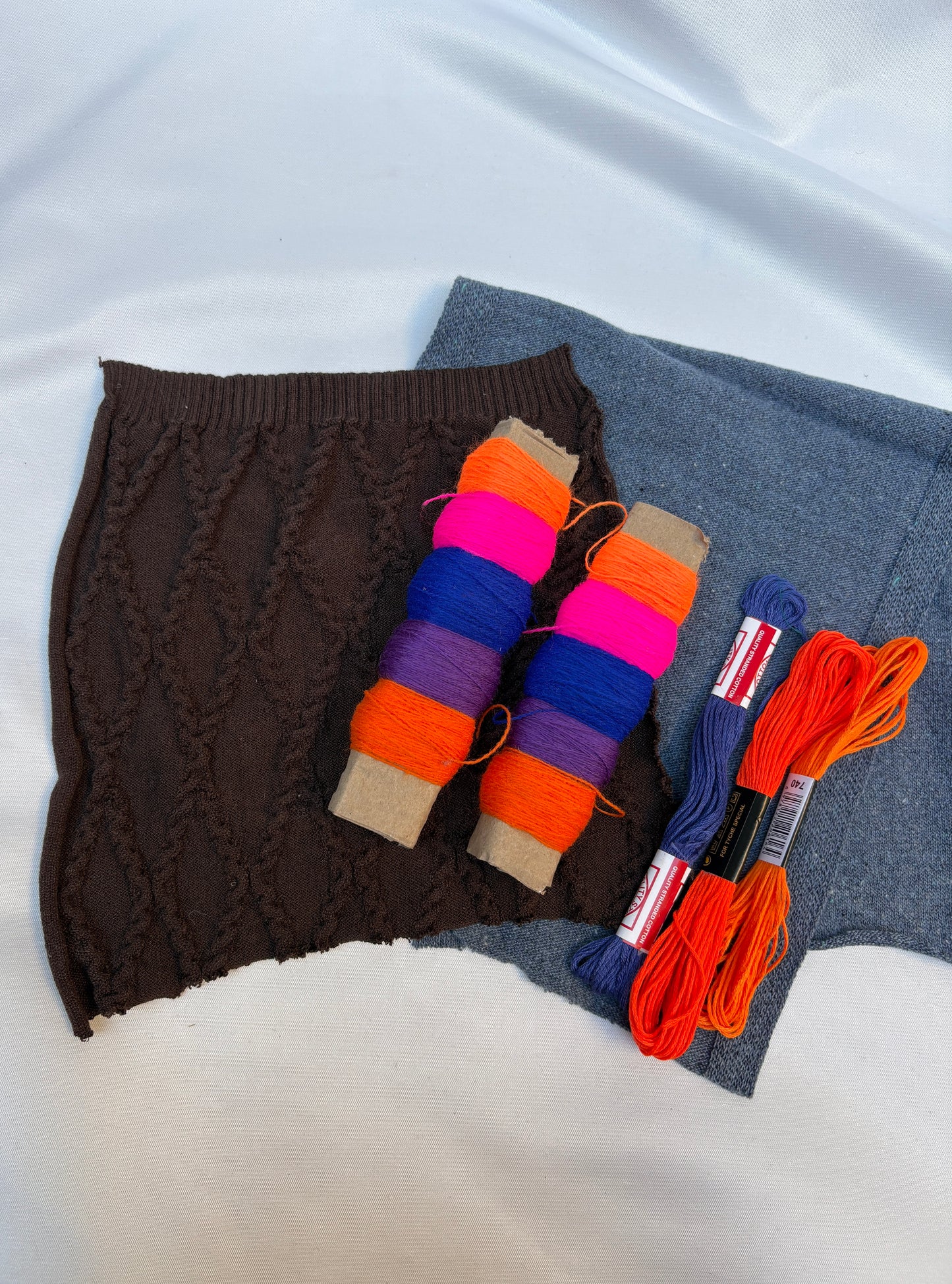 Textured fabric swatches with bright thread spools and embroidery floss.