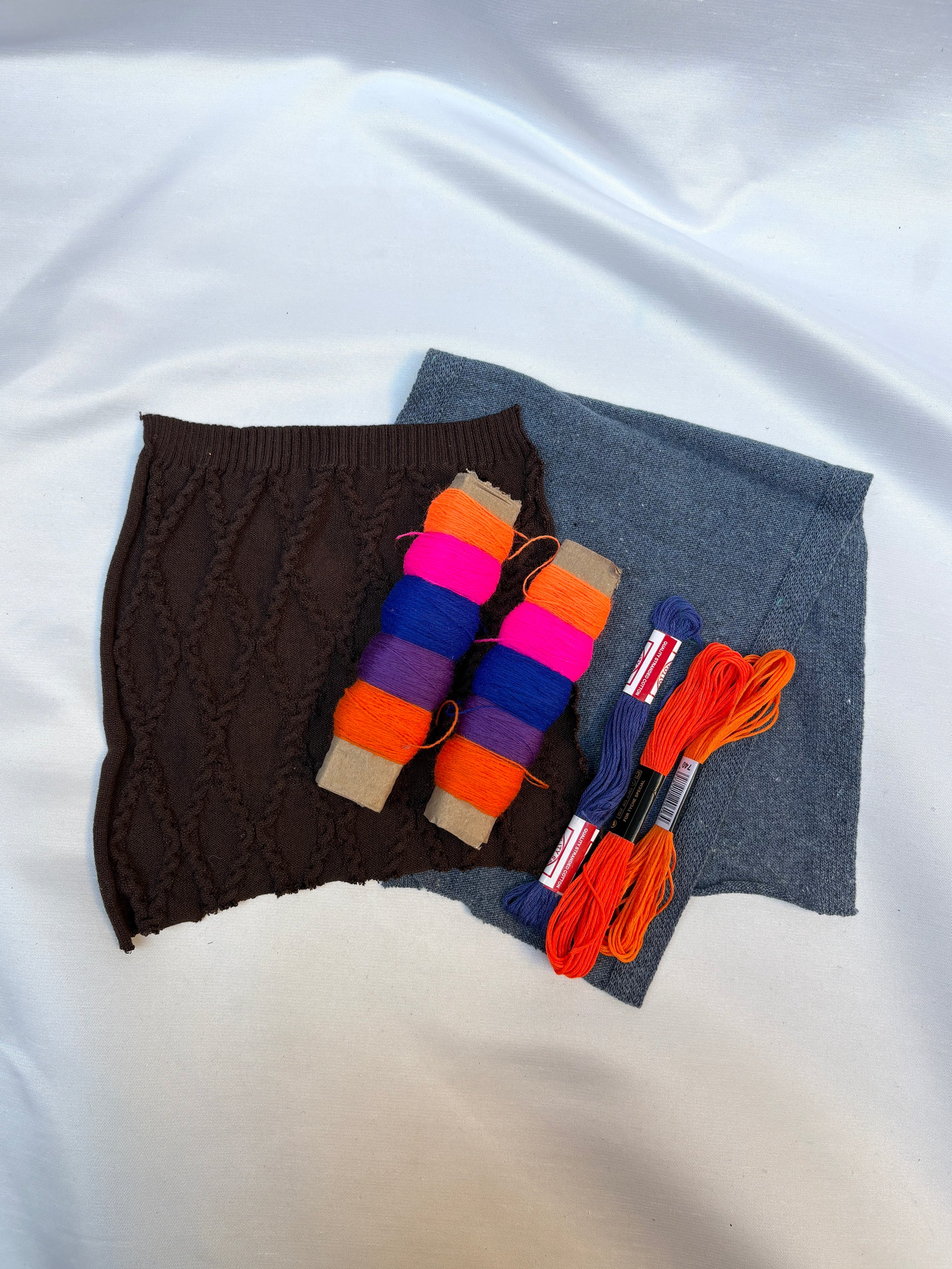 Fabric swatches paired with vivid thread spools and embroidery floss.