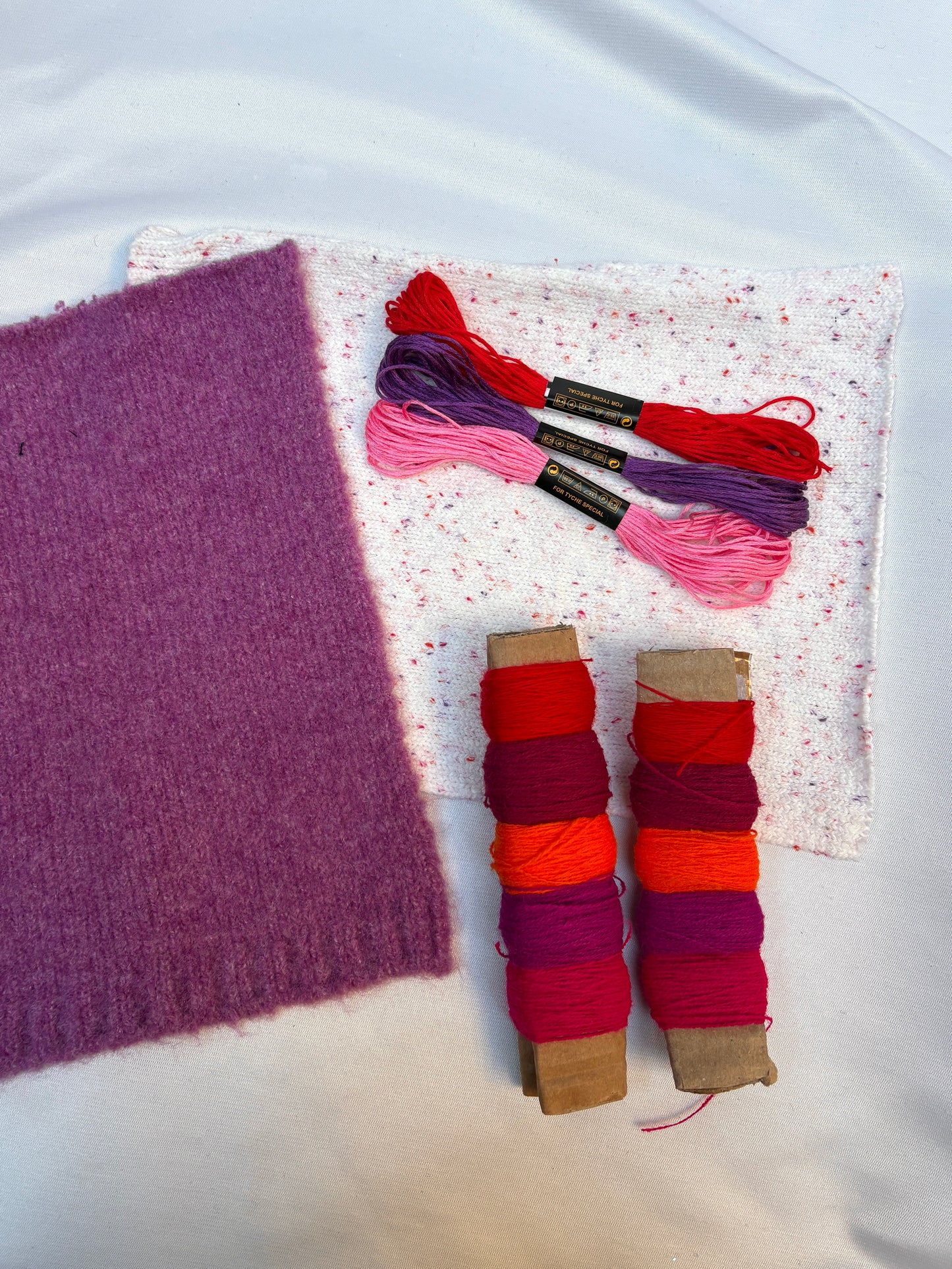 Soft fabric swatches with bright thread spools and embroidery floss.