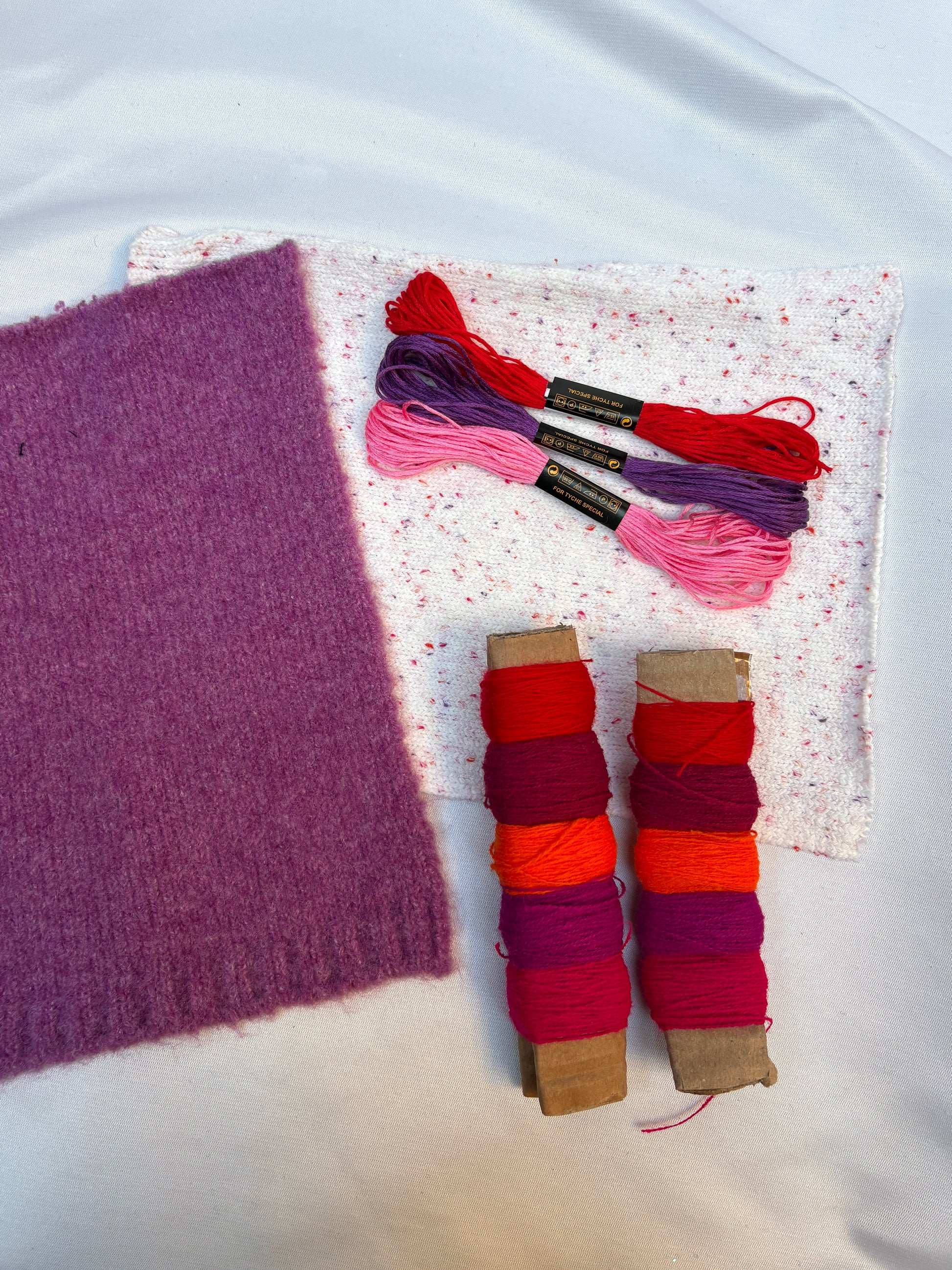Soft fabric swatches with bright thread spools and embroidery floss.