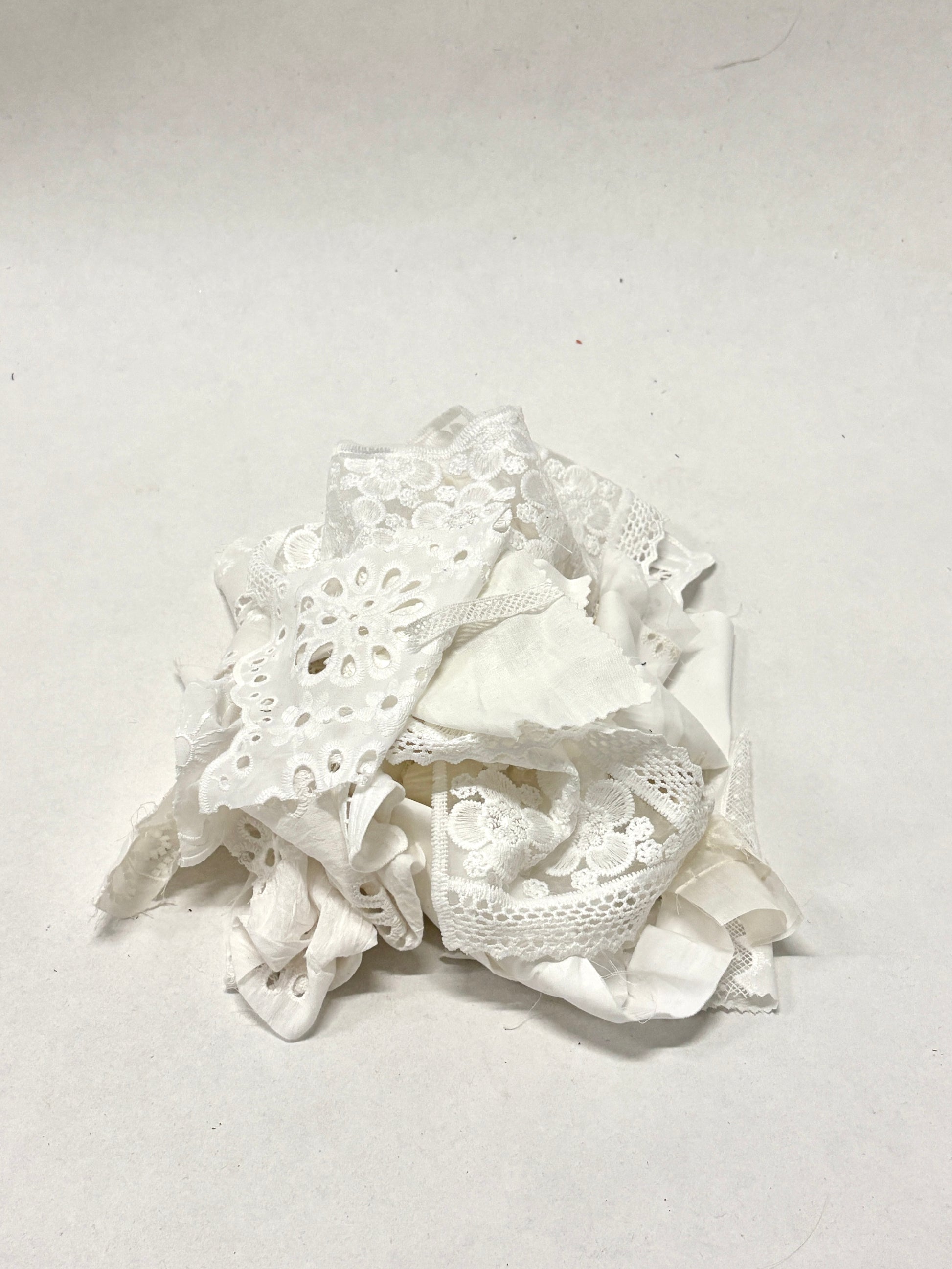 A pile of decorative lace textiles offcuts samples in white