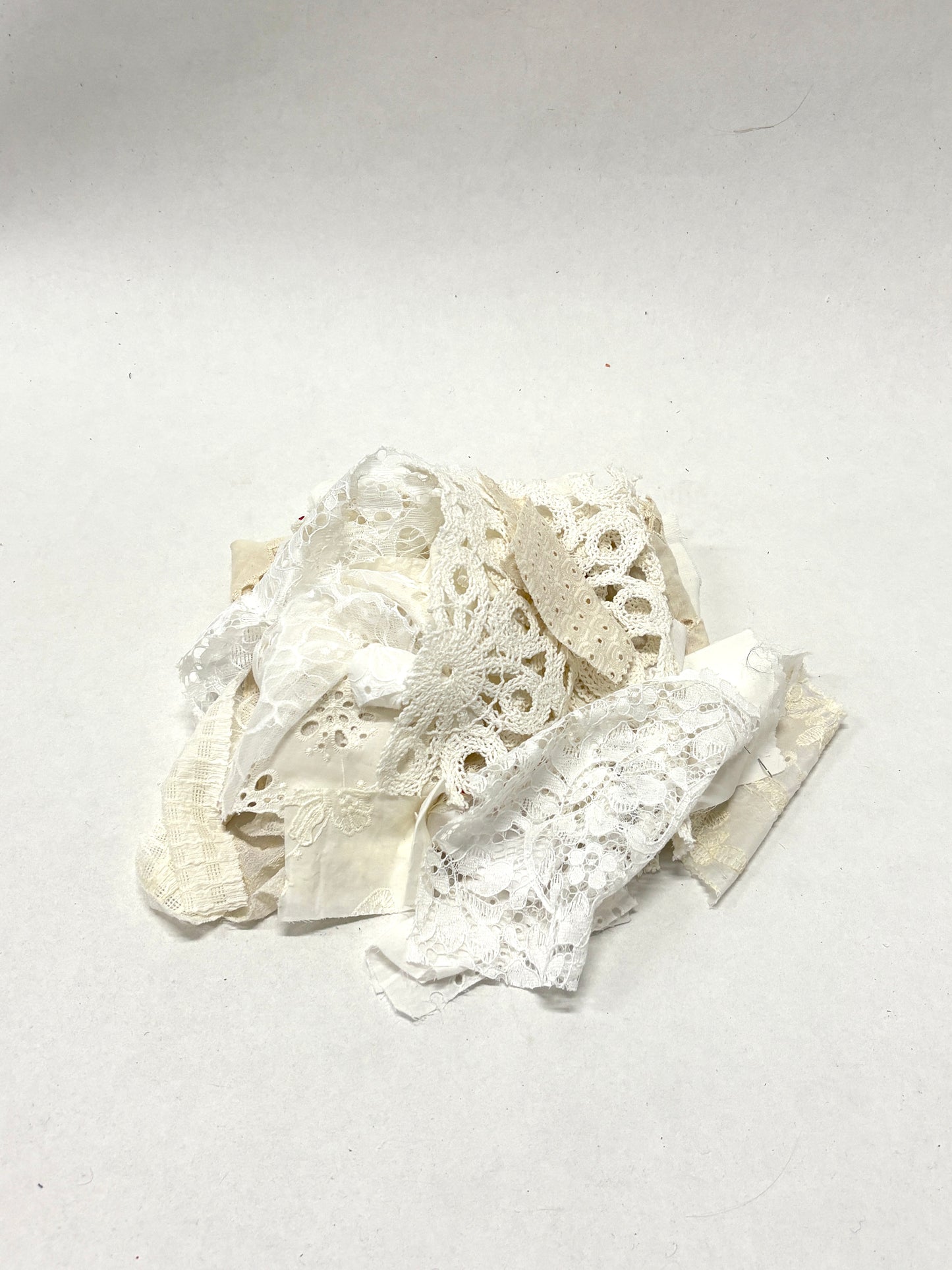 A pile of decorative lace textiles offcuts samples in white