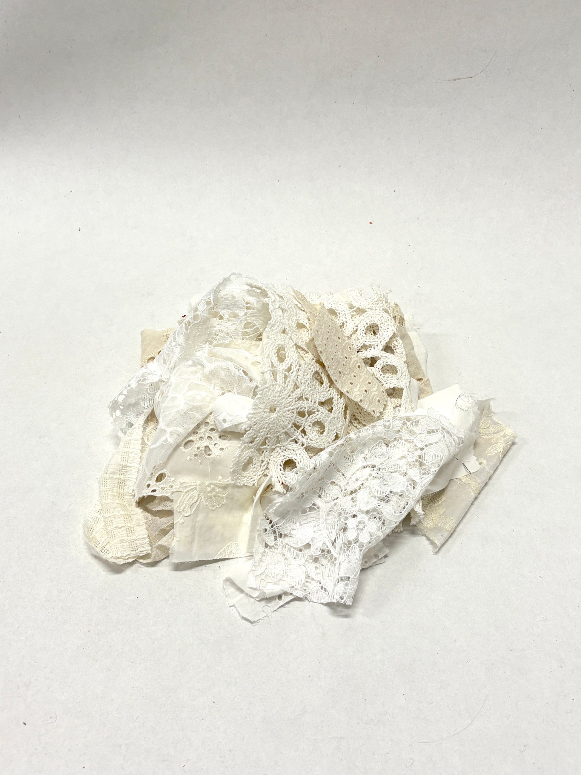 A pile of decorative lace textiles offcuts samples in white