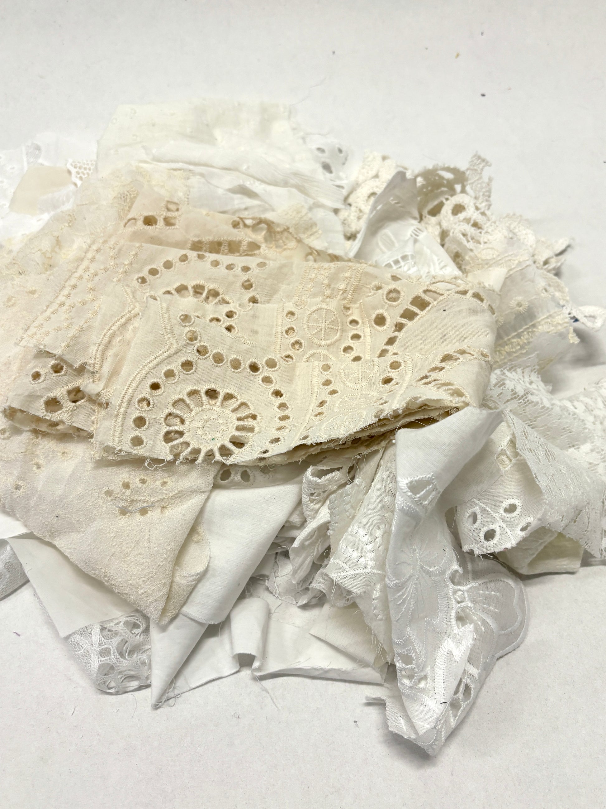 A pile of decorative lace textiles offcuts samples in white