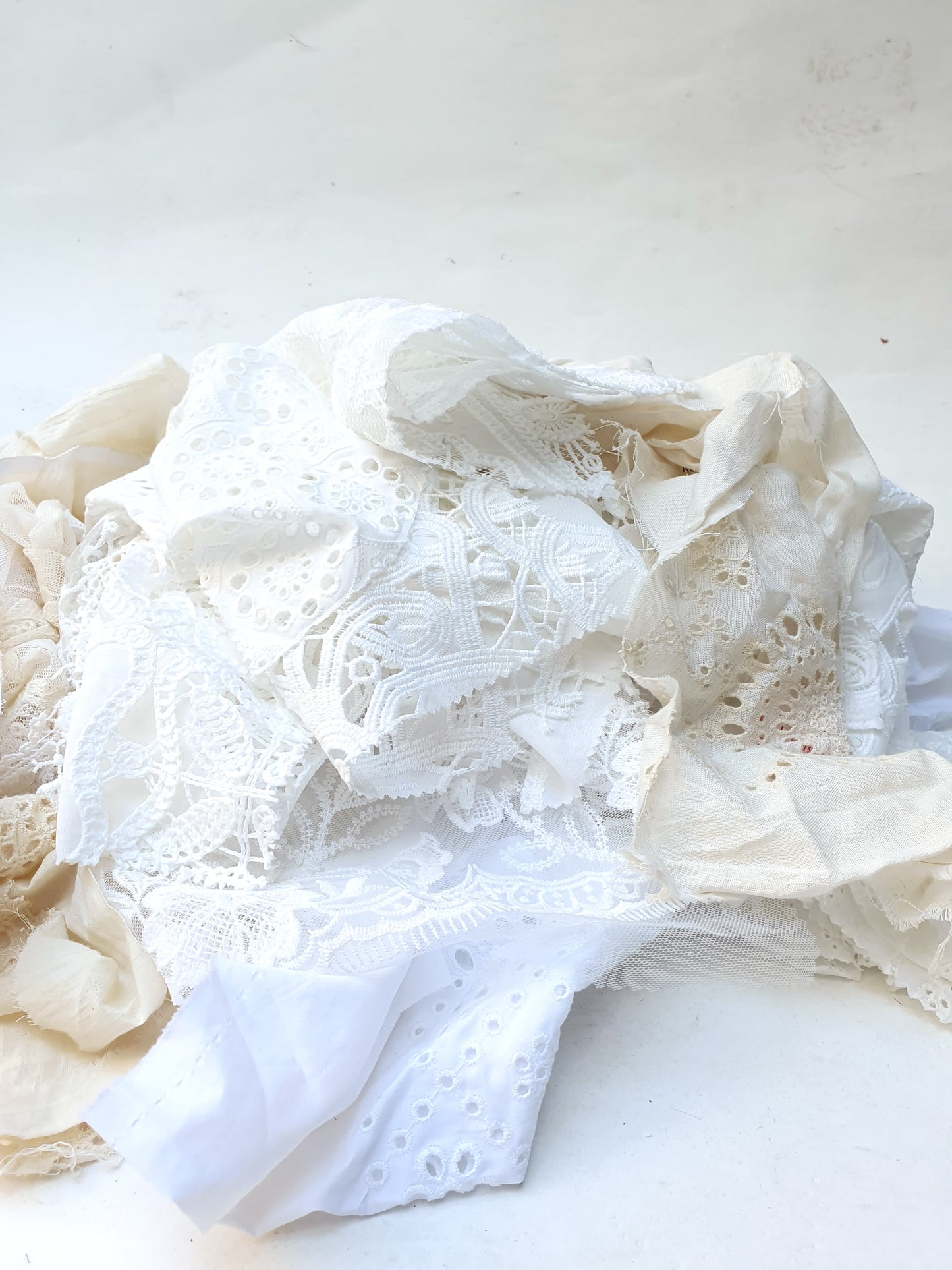 A pile of decorative lace textiles offcuts samples in white