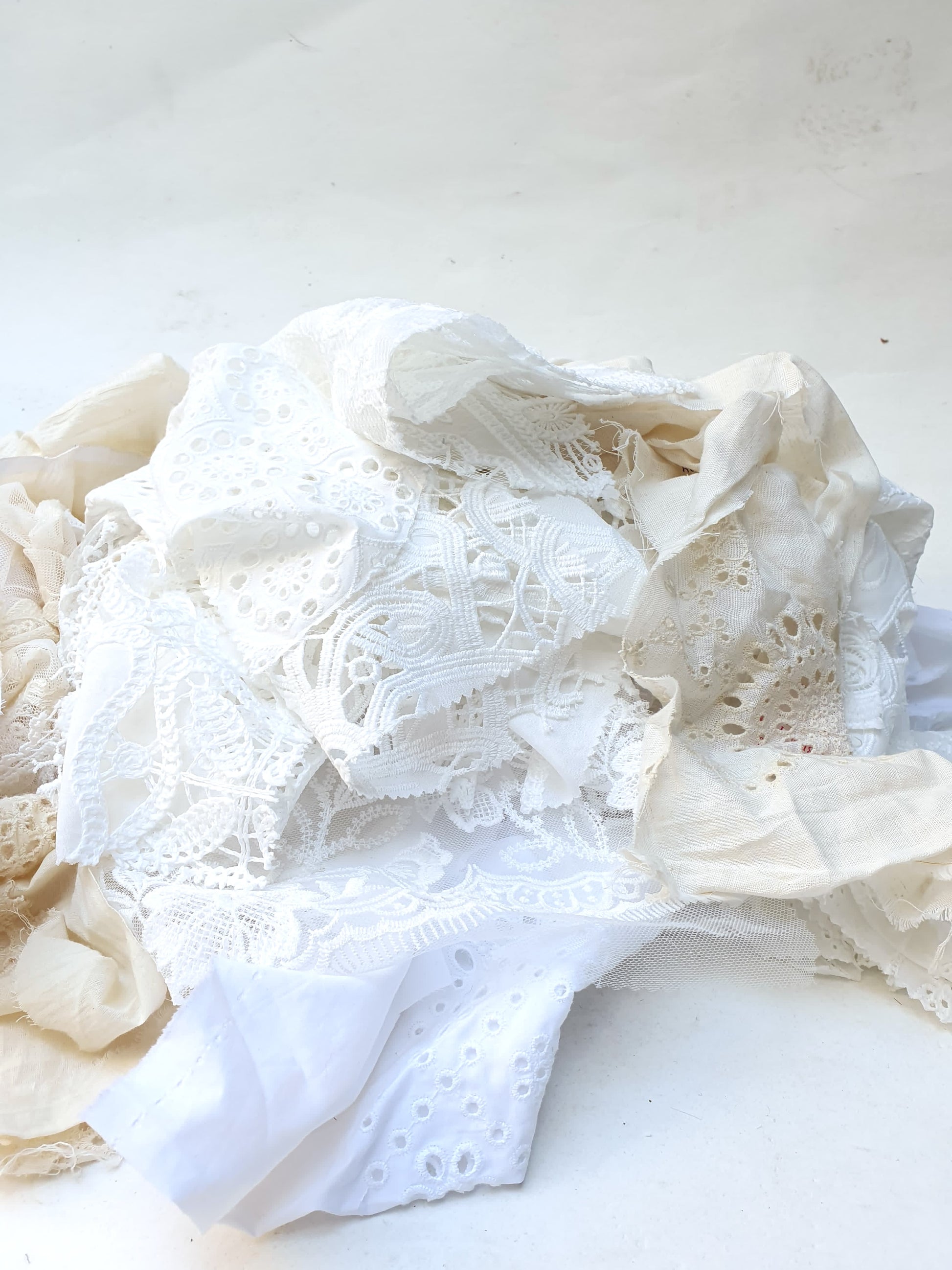 A pile of decorative lace textiles offcuts samples in white