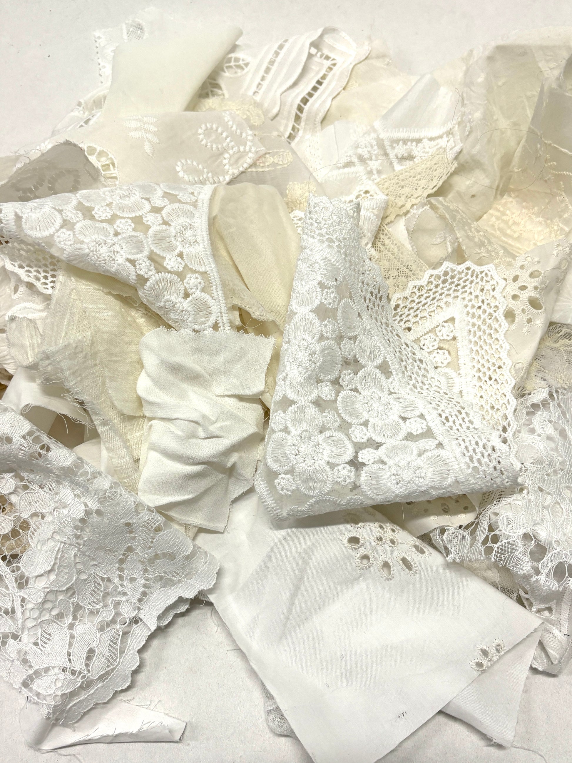 A pile of decorative lace textiles offcuts samples in white