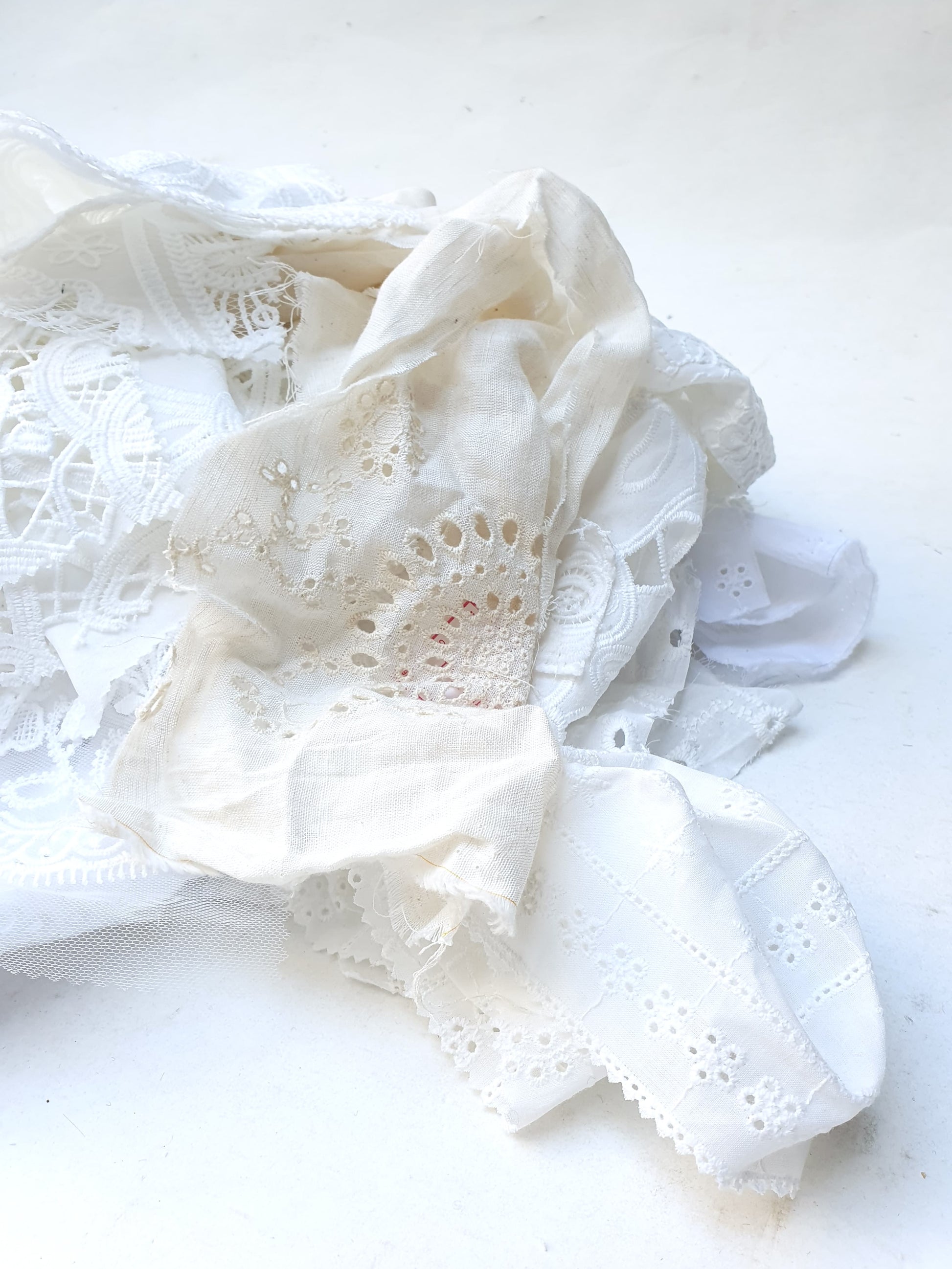 A pile of decorative lace textiles offcuts samples in white