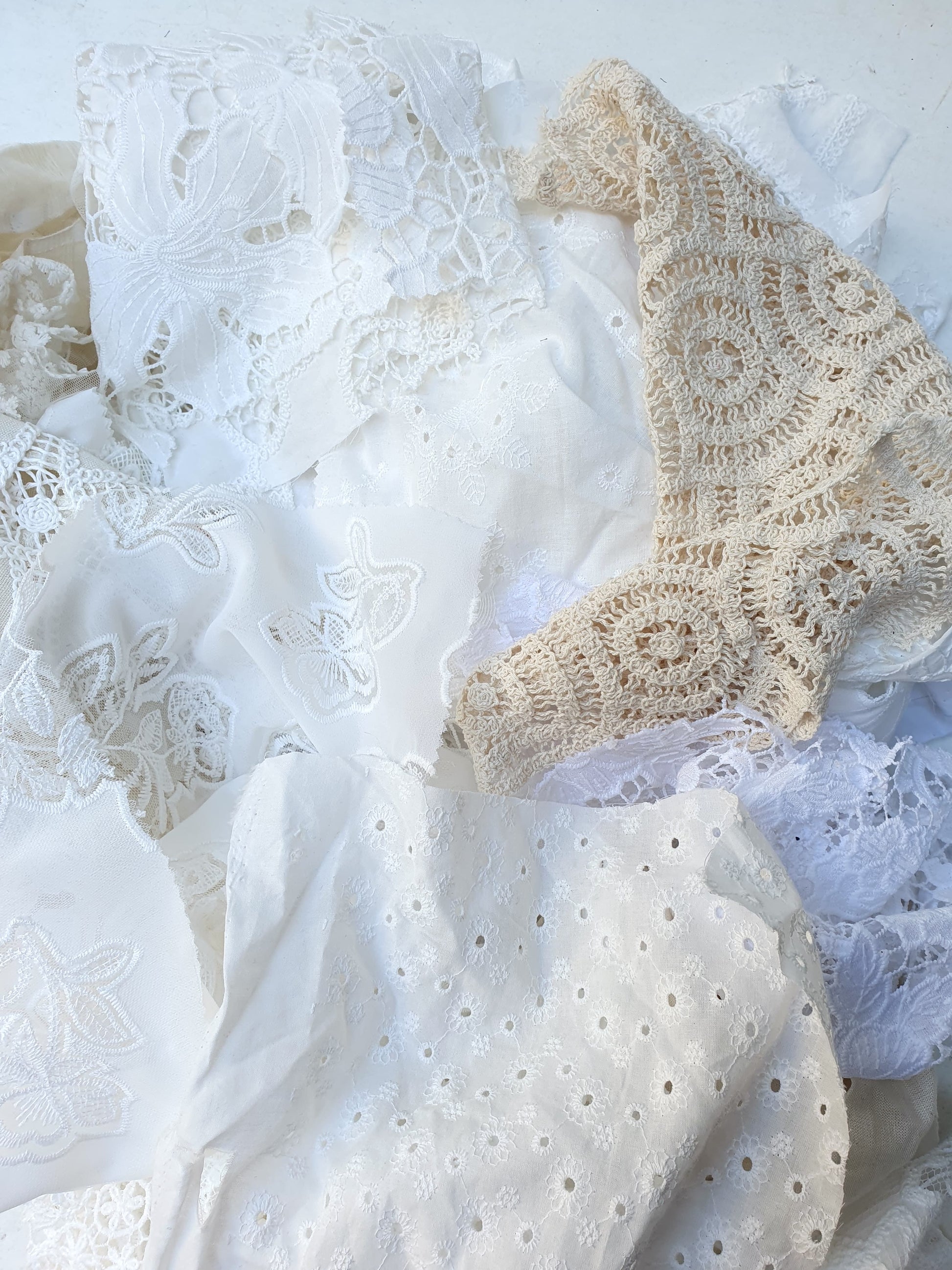 A pile of decorative lace textiles offcuts samples in white