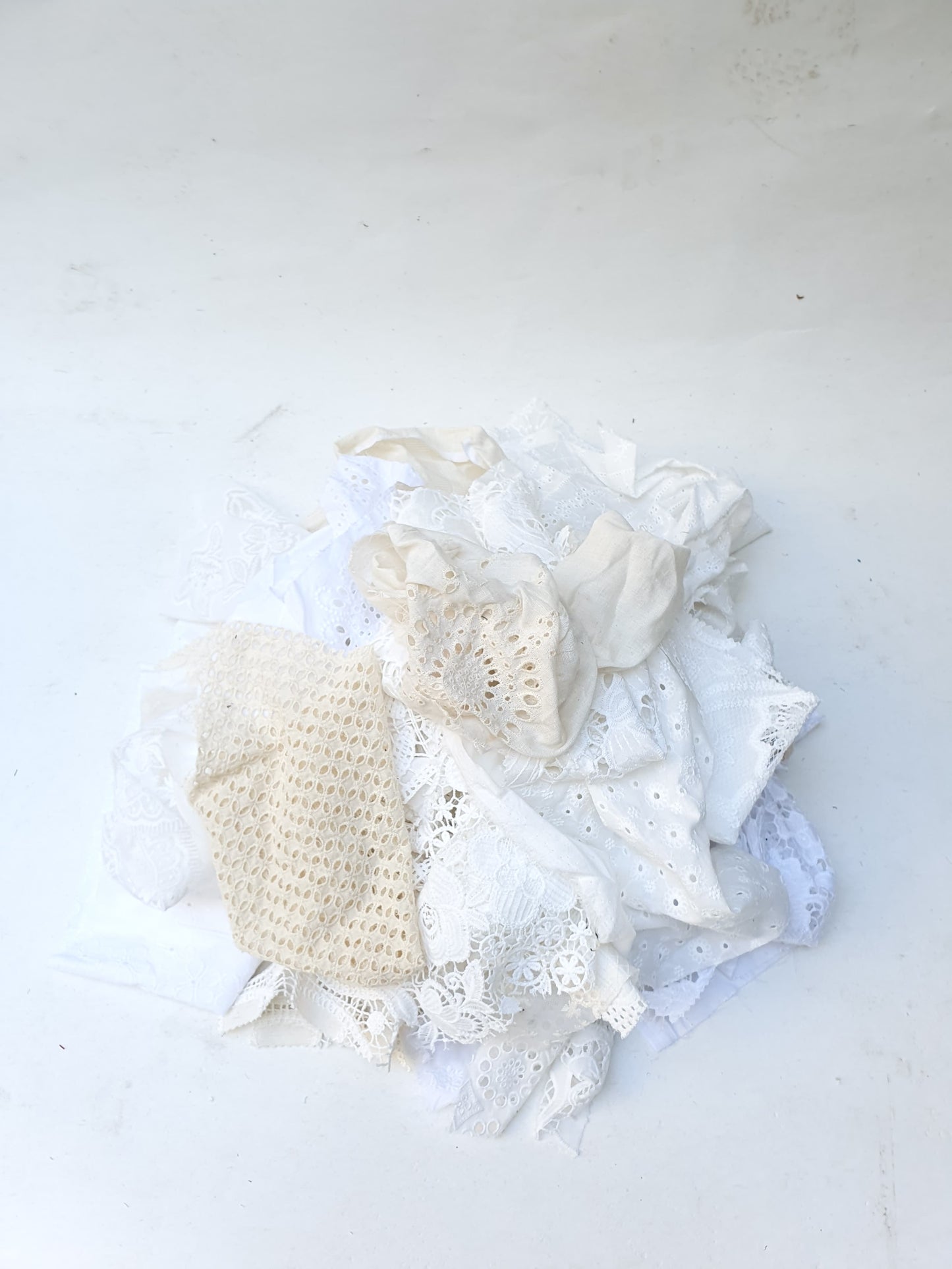 A pile of decorative lace textiles offcuts samples in white