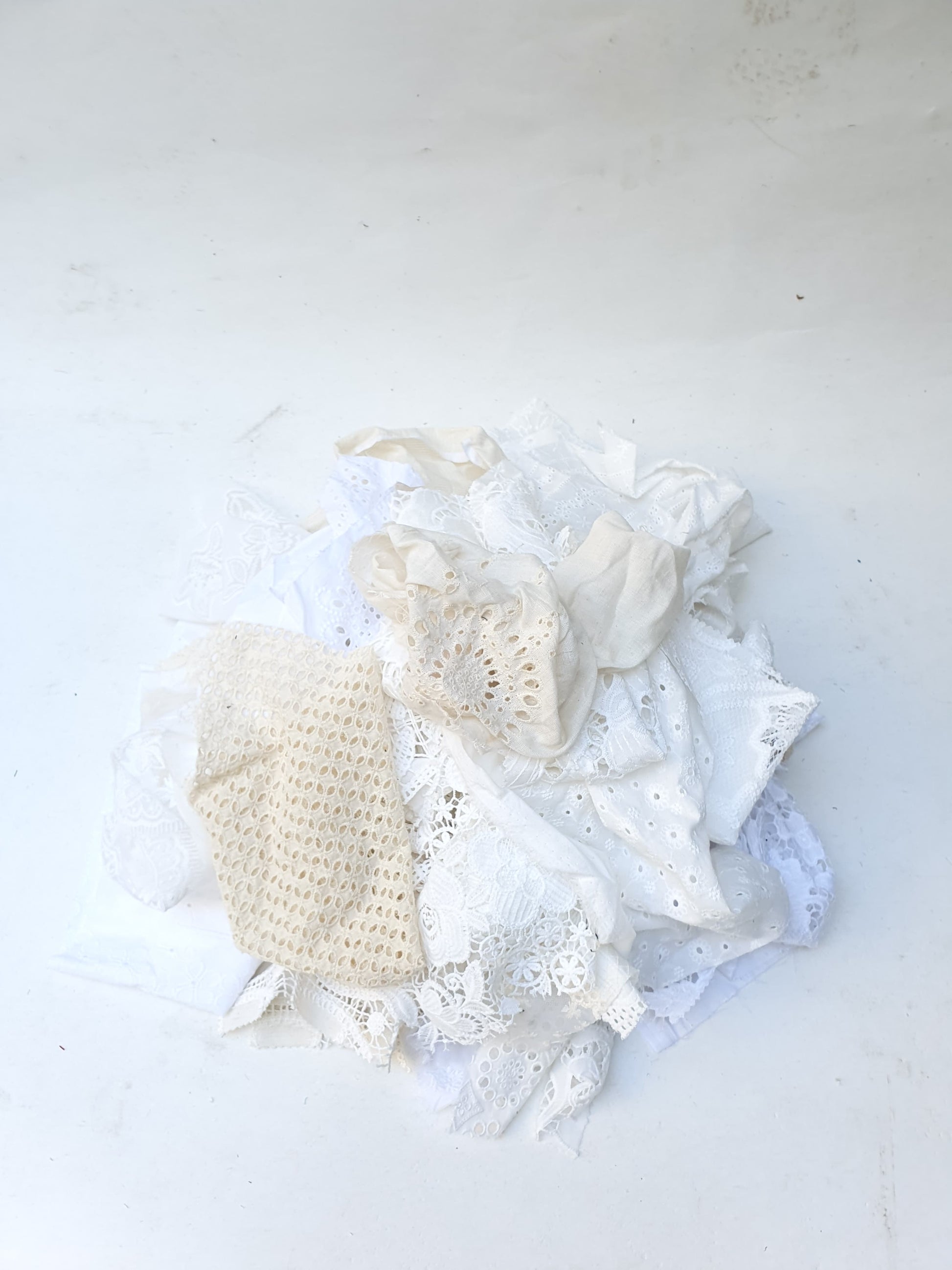 A pile of decorative lace textiles offcuts samples in white