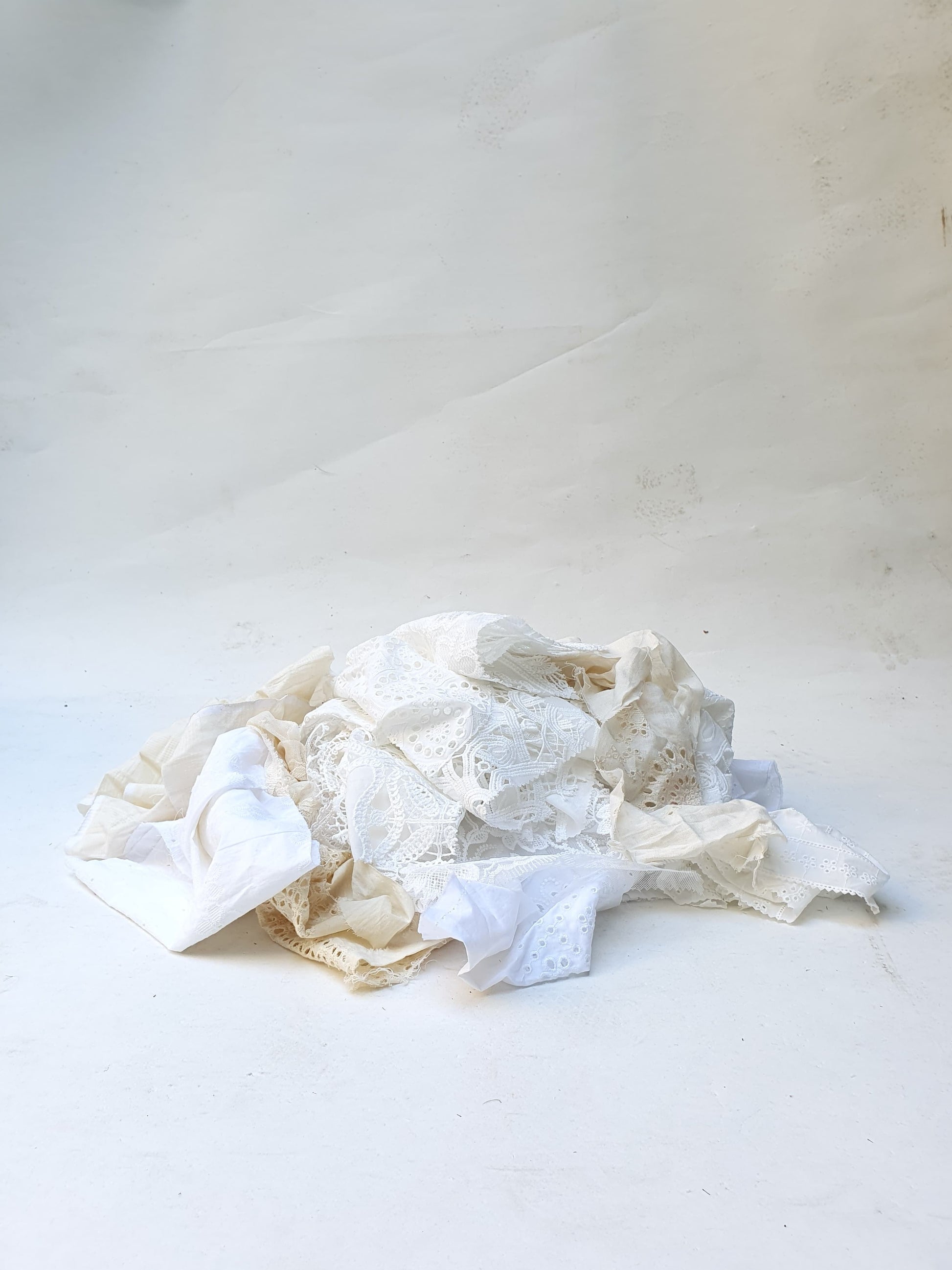 A pile of decorative lace textiles offcuts samples in white