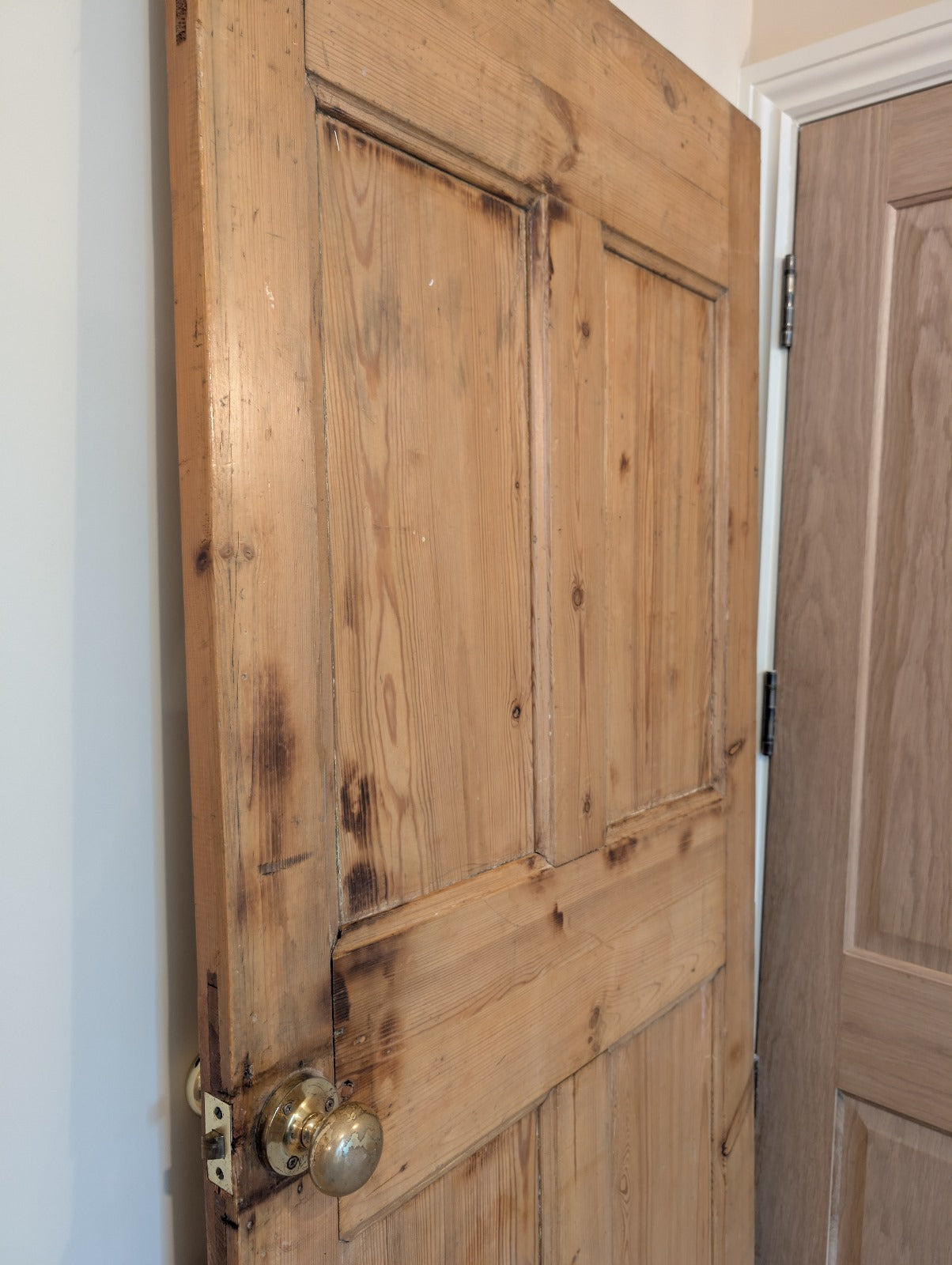 An old pine door with a dark stain, featuring a handle, showing natural ageing patterns.