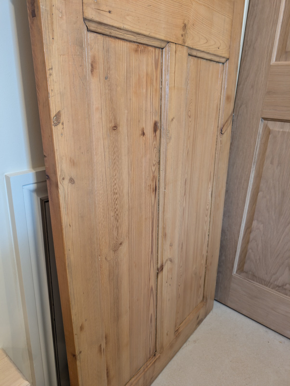 An old pine door with a dark stain, featuring a handle, showing natural ageing patterns.