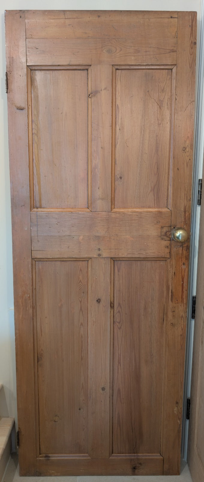 An old pine door with a dark stain, featuring a handle, showing natural ageing patterns.