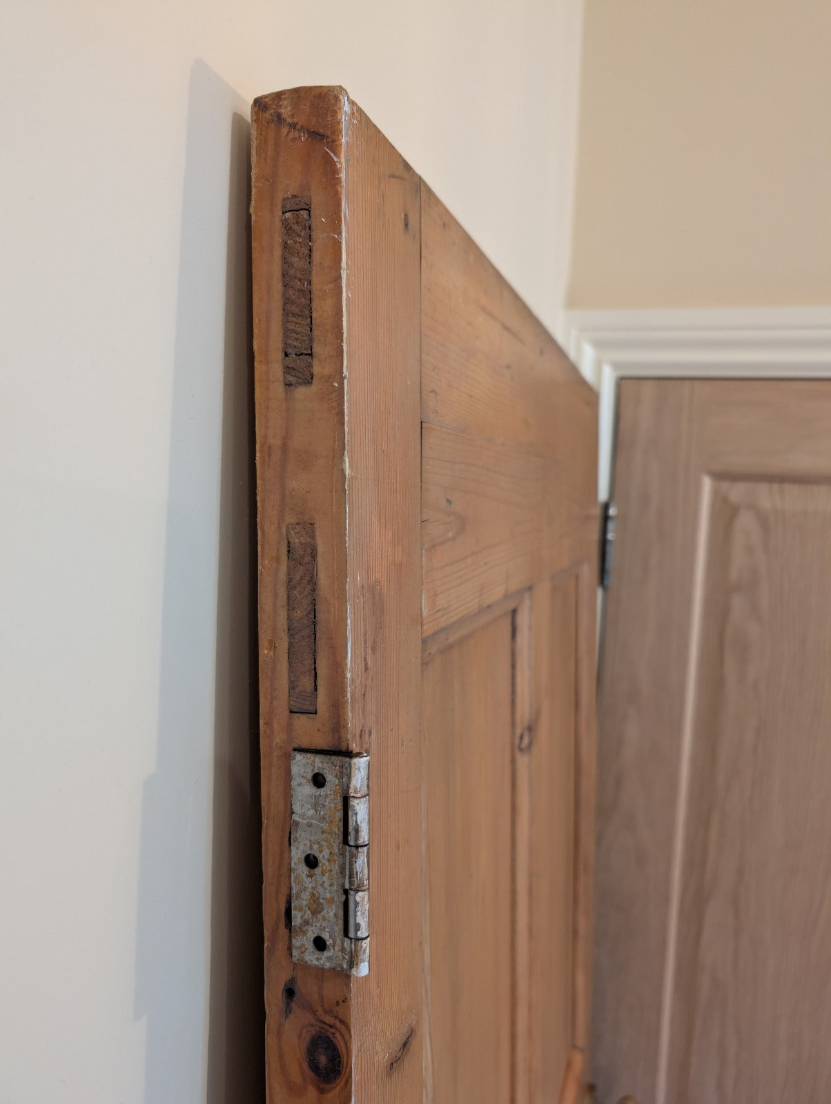 An old pine door with a dark stain, featuring a handle, showing natural ageing patterns.