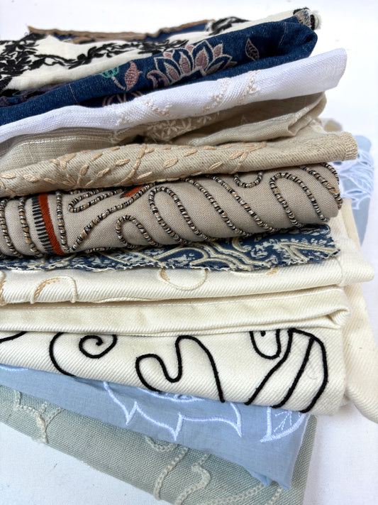 Stack of embroidered fabric samples with various patterns and colours.