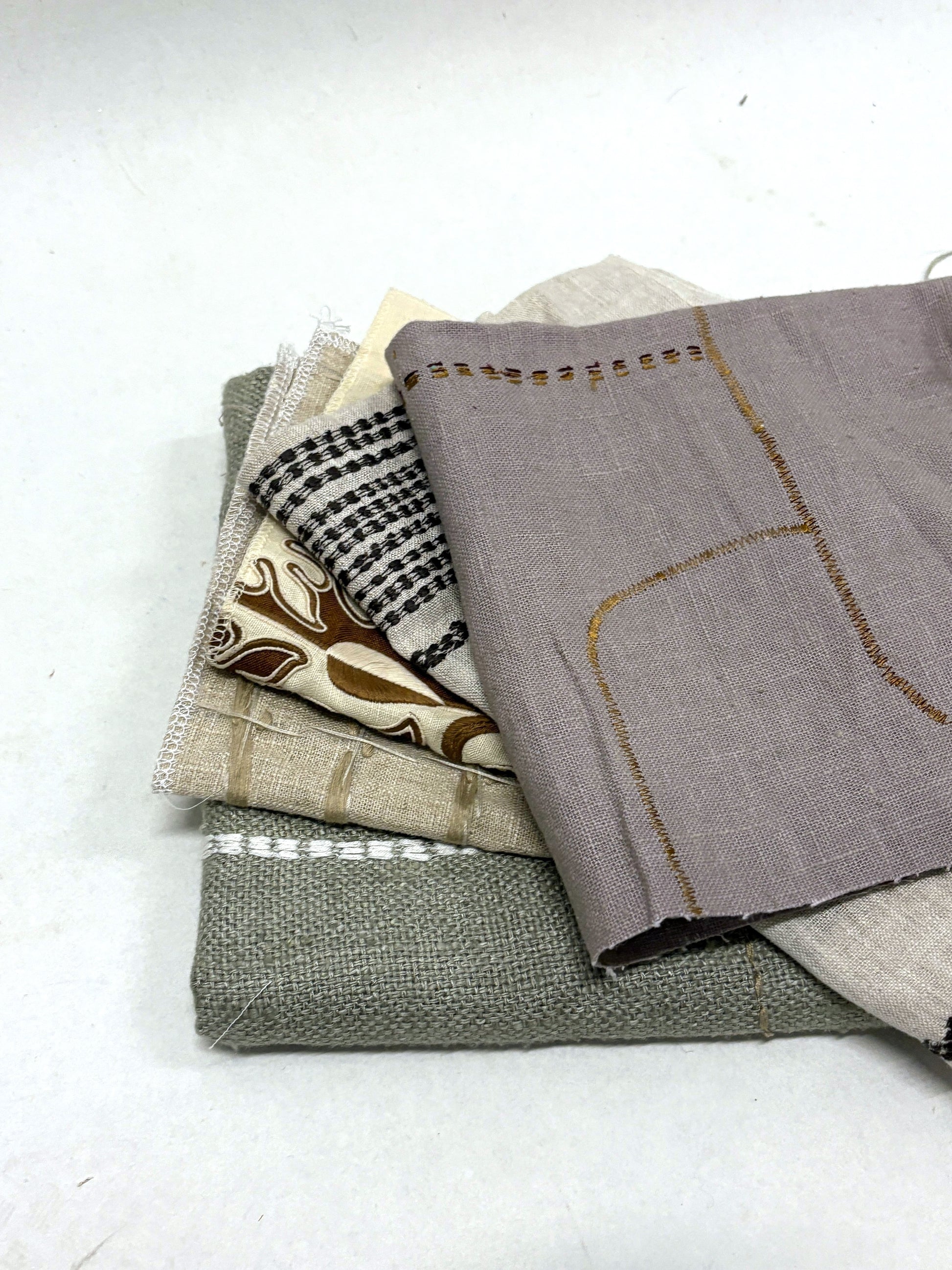 Stack of embroidered fabric samples with various patterns and colours.