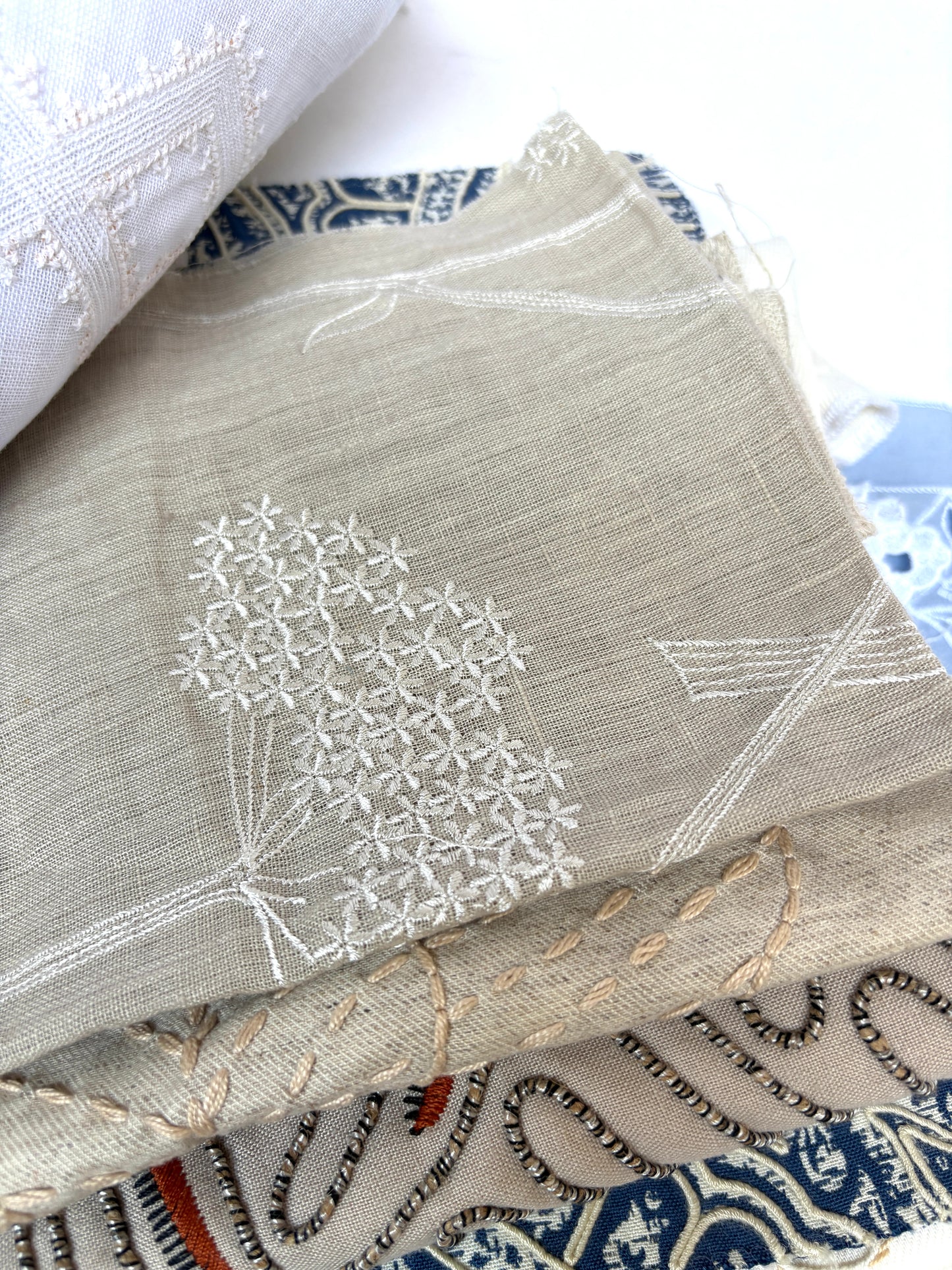 Stack of embroidered fabric samples with various patterns and colours.