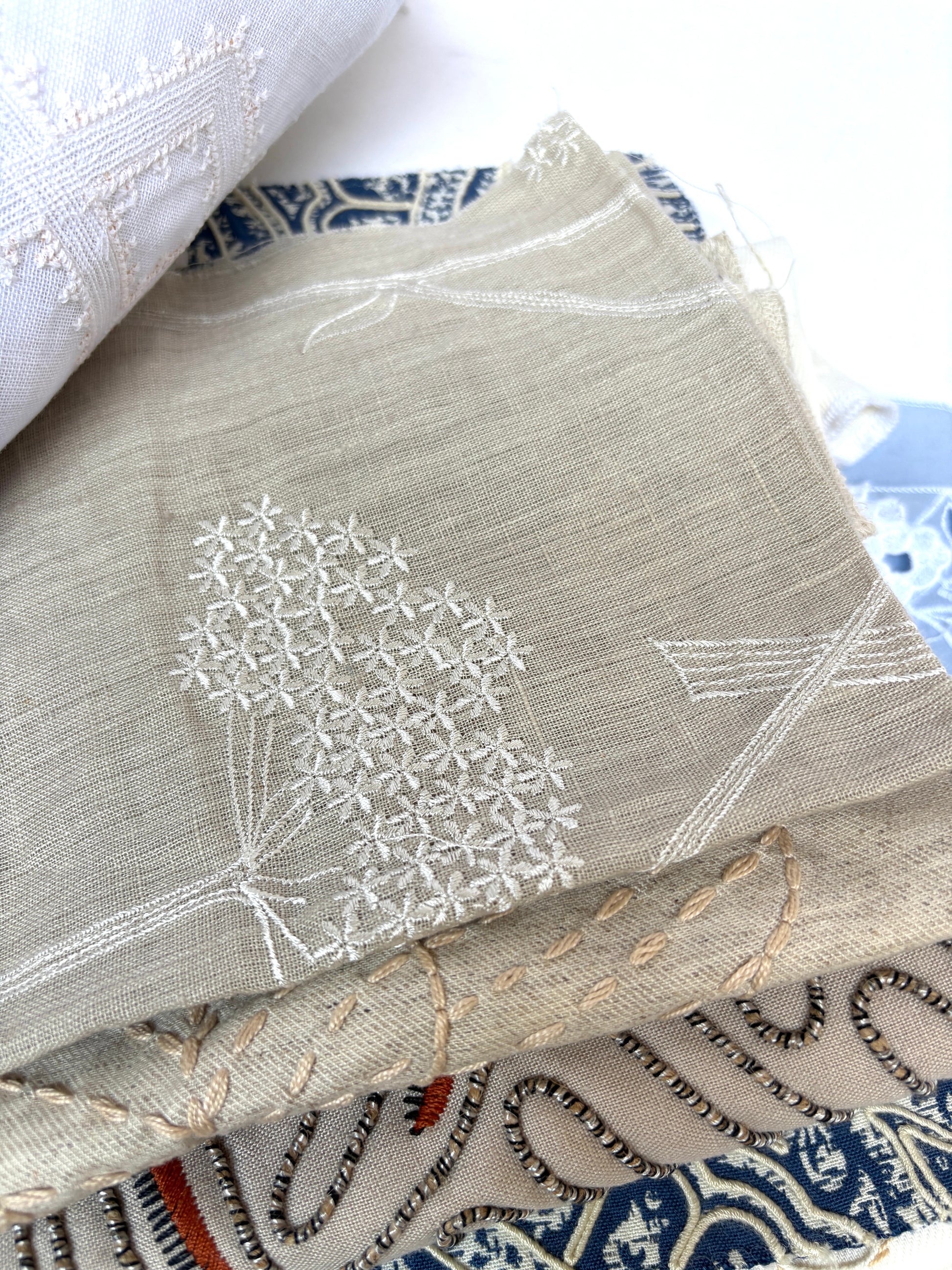 Stack of embroidered fabric samples with various patterns and colours.
