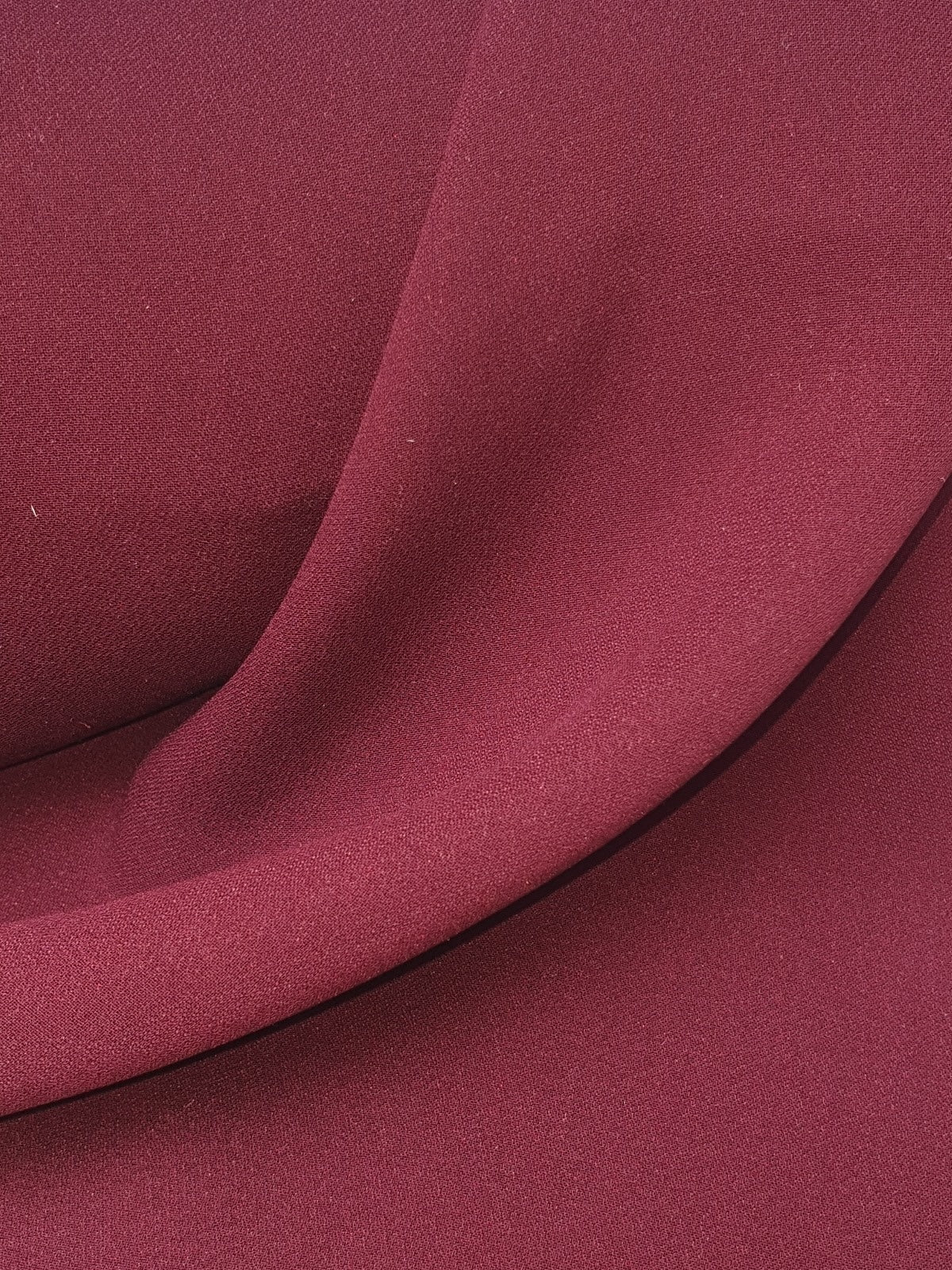 Close-up of light weighted fabric in burgundy, soft texture visible 