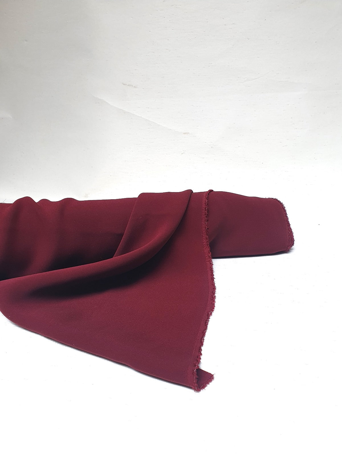 Roll of light weighted fabric in burgundy, soft texture visible 