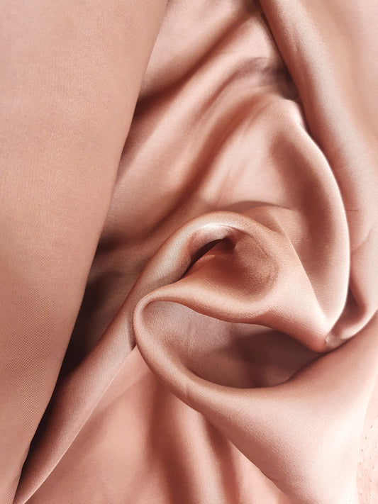 Close-up of charmeuse fabric in pink, shiny texture visible 