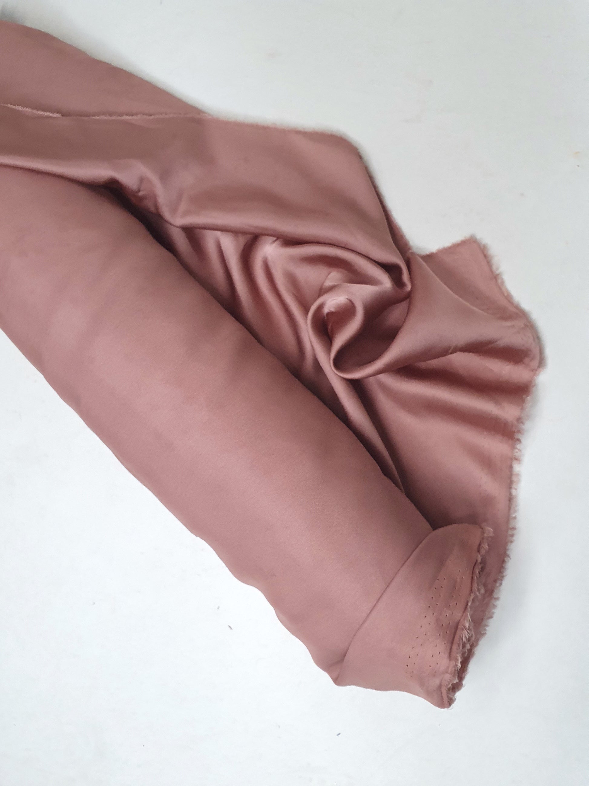 Charmeuse fabric in pink, shiny texture visible 