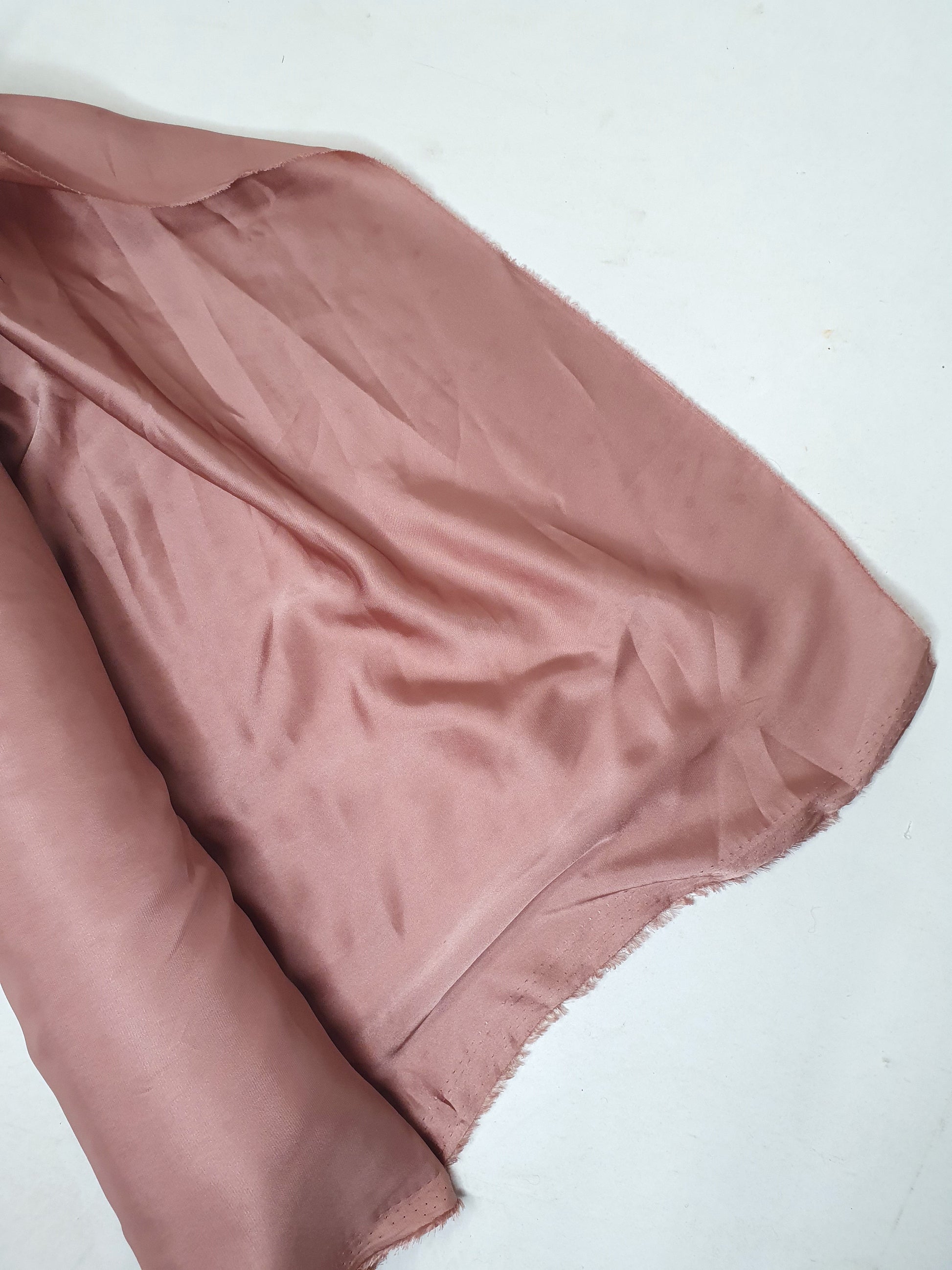Charmeuse fabric in pink, shiny texture visible 