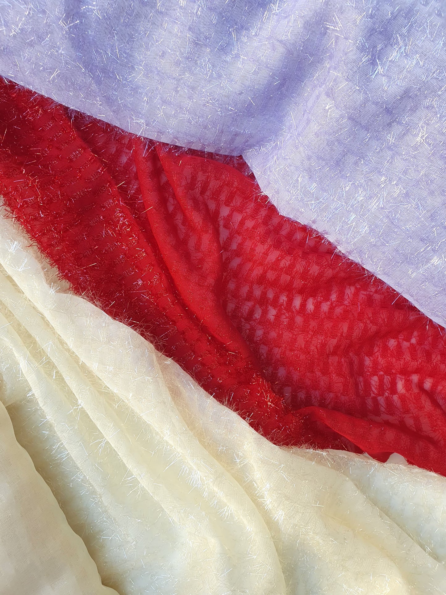 Close-up of sparkly embroidered fabric in red, lilac and cream