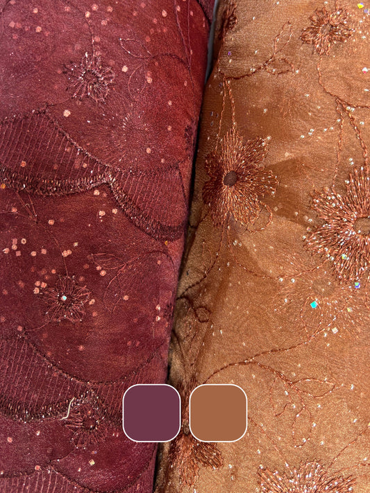 Close-up of embroidered lace fabric with floral patterns in bronze and burgundy with colour swatch below 
