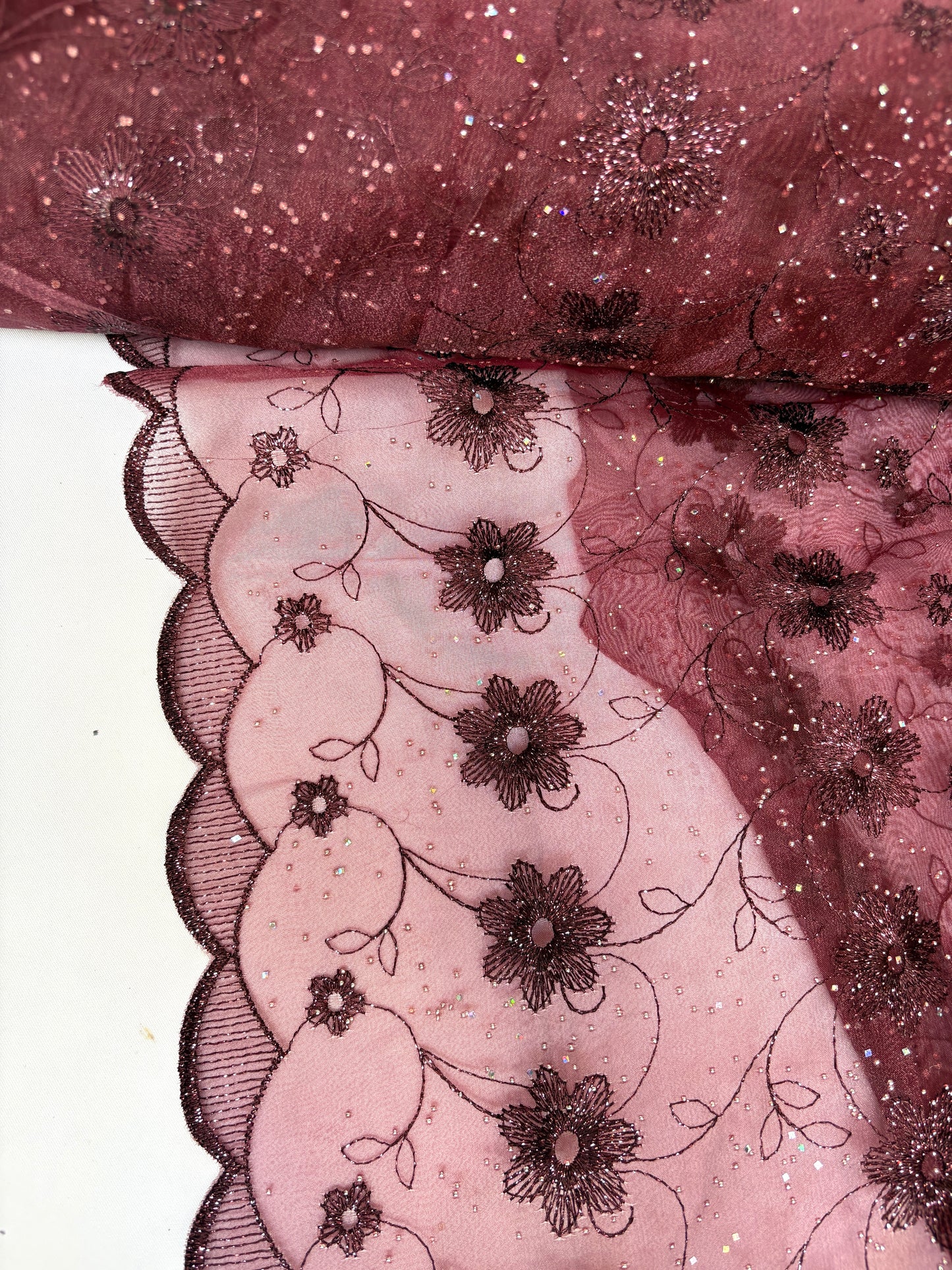 Close-up of embroidered lace fabric with floral patterns in burgundy