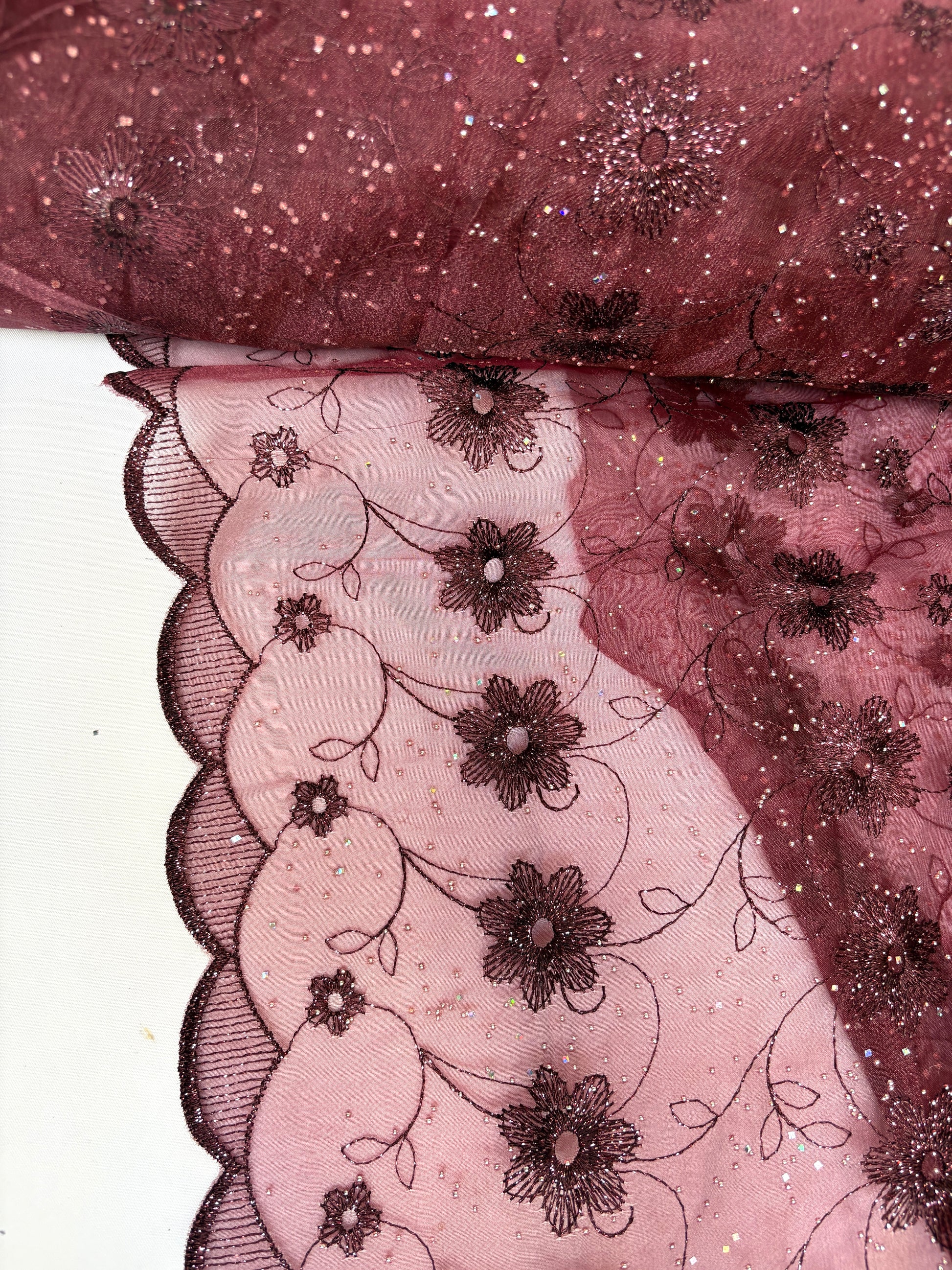 Close-up of embroidered lace fabric with floral patterns in burgundy