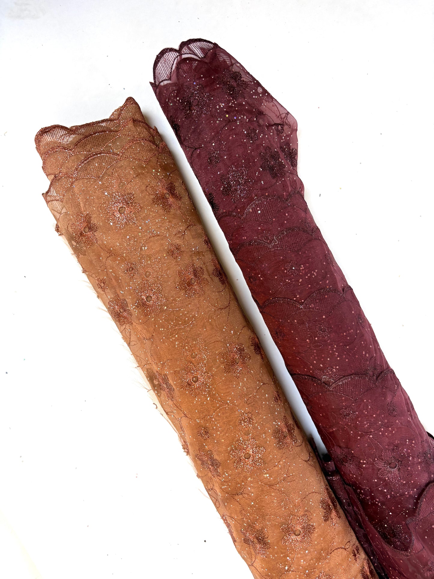 Two rolls of embroidered fabric with floral patterns in brown and red tones.