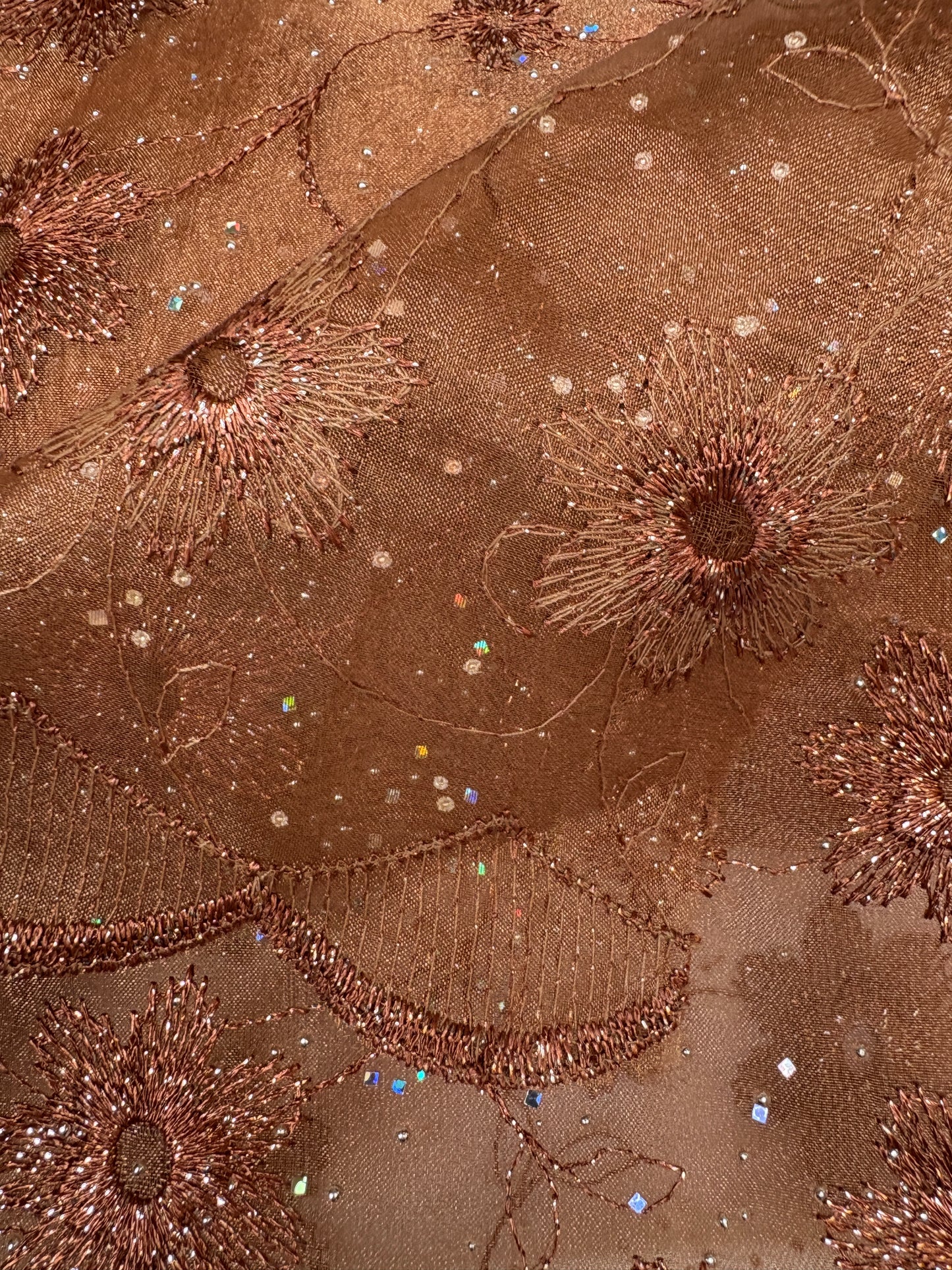 Close-up of embroidered fabric with floral patterns in bronze