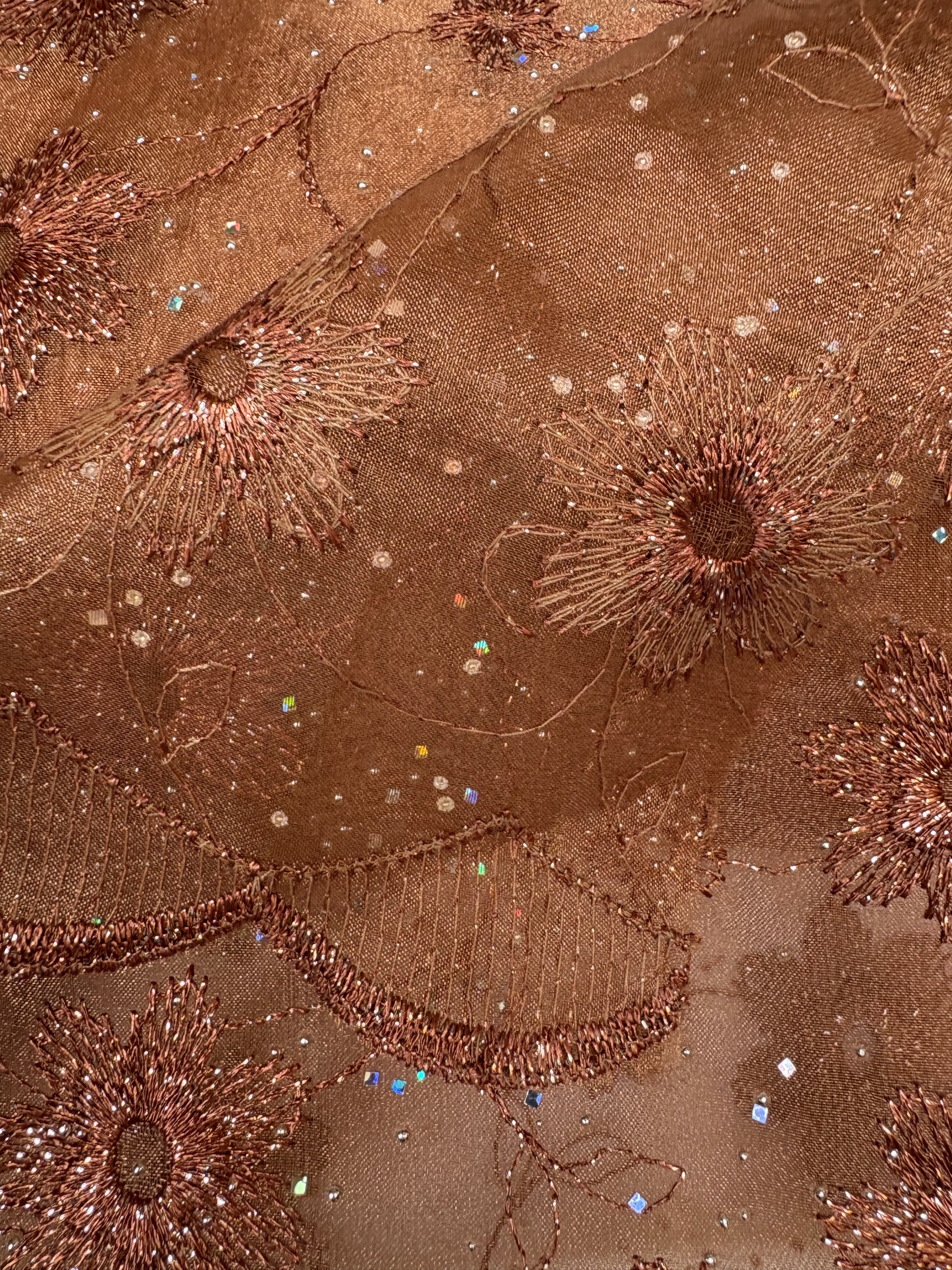 Close-up of embroidered fabric with floral patterns in bronze