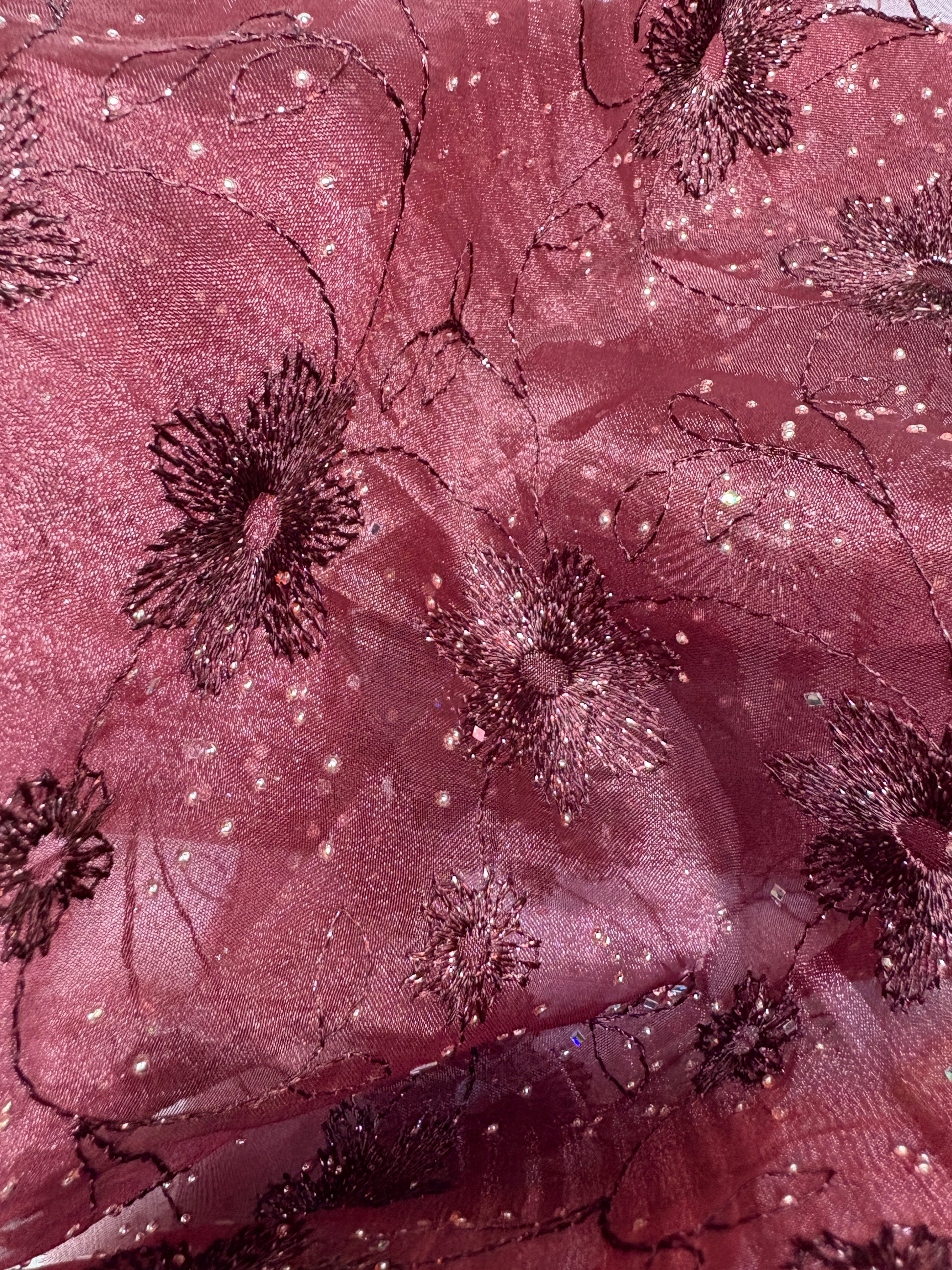 Close-up of embroidered fabric with floral patterns in burgundy.