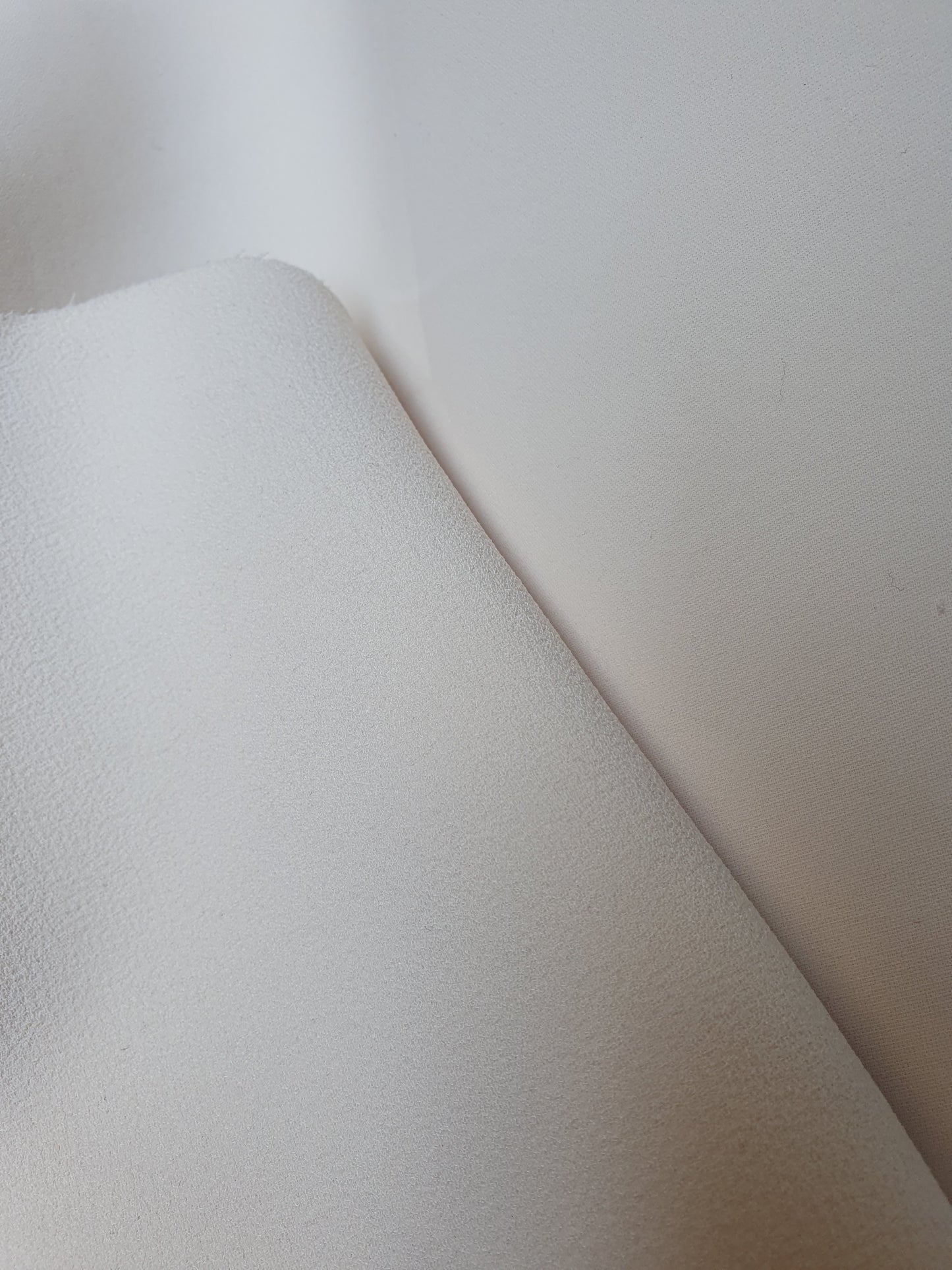 Close-up of heavy double-backed fabric in cream white, soft texture visible 