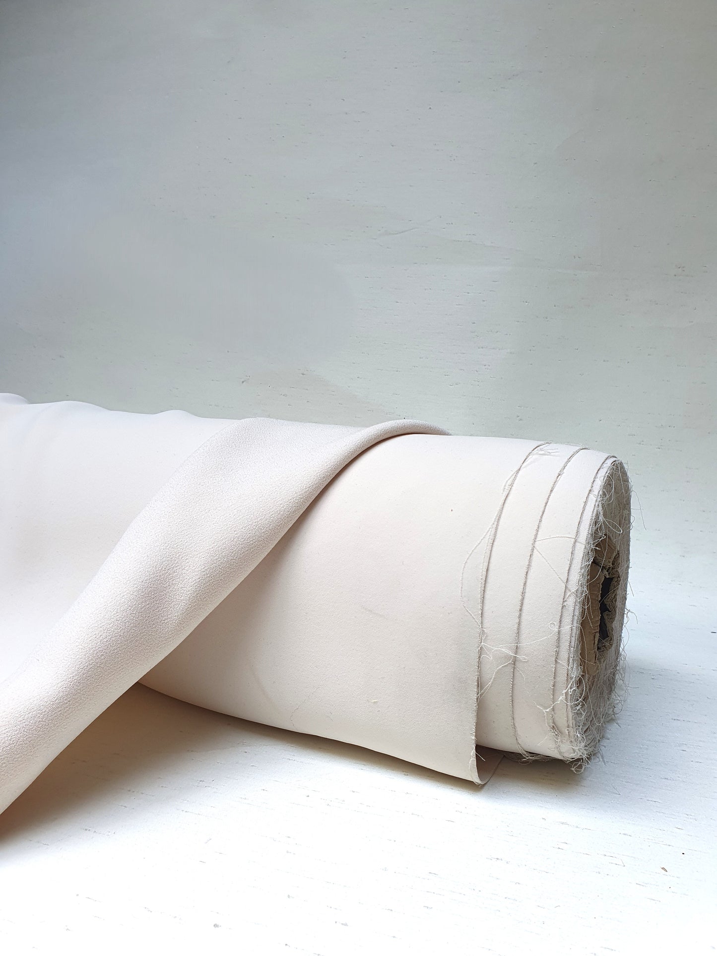 Roll of heavy double-backed fabric in cream white, soft texture visible 