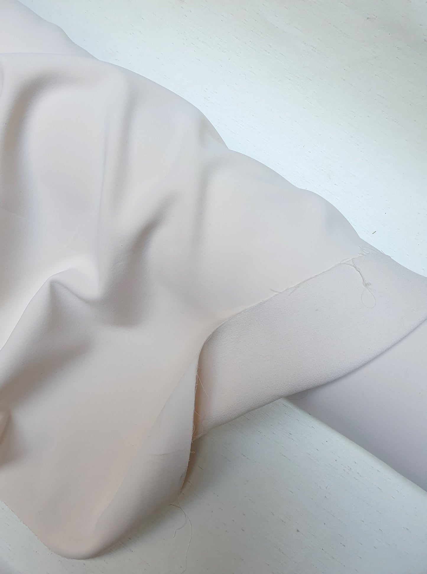 Close-up of heavy double-backed fabric in cream white, soft texture visible 