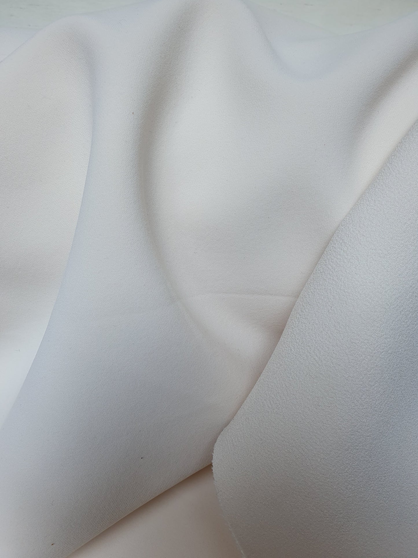 Close-up of heavy double-backed fabric in cream white, soft texture visible 