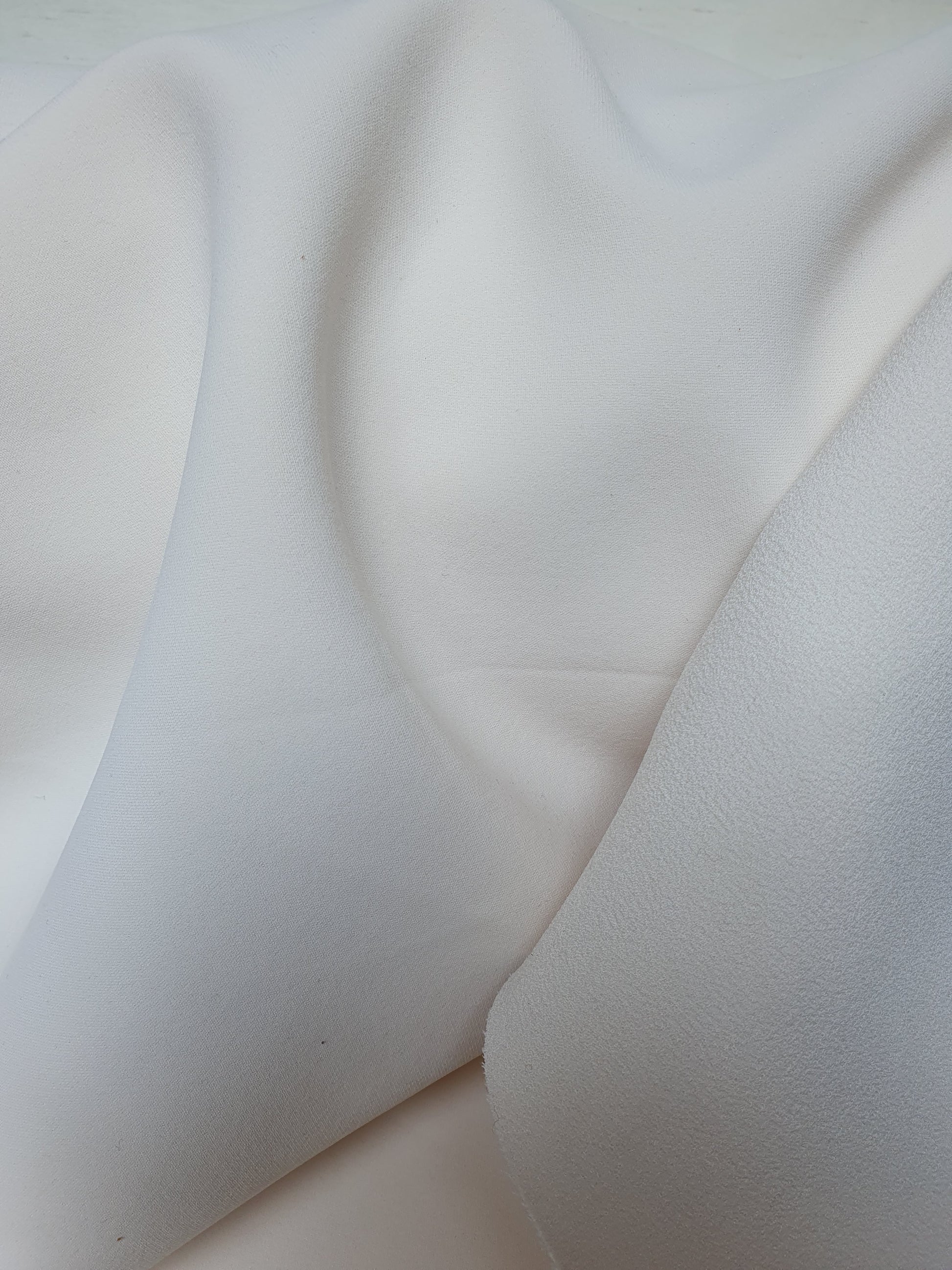 Close-up of heavy double-backed fabric in cream white, soft texture visible 